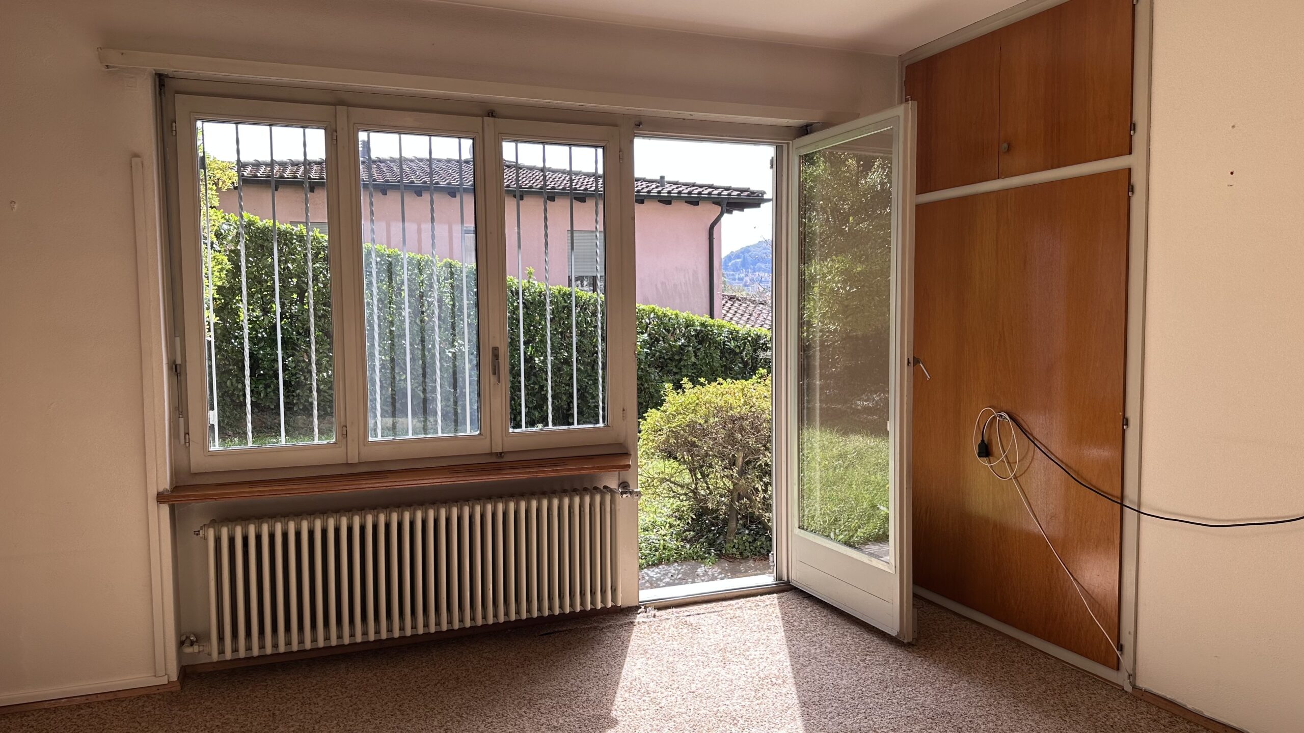 Helles Zimmer mit geöffnetem Fenster und Blick ins Grüne