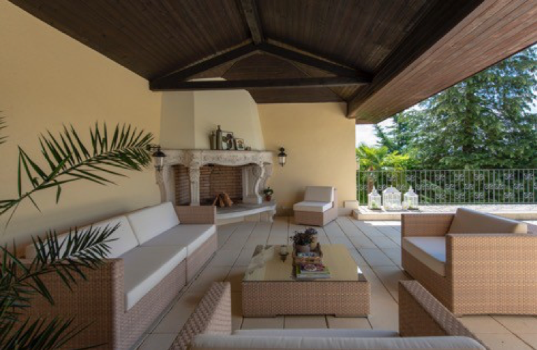 Überdachte Terrasse mit Sitzgruppe und offenem Kamin