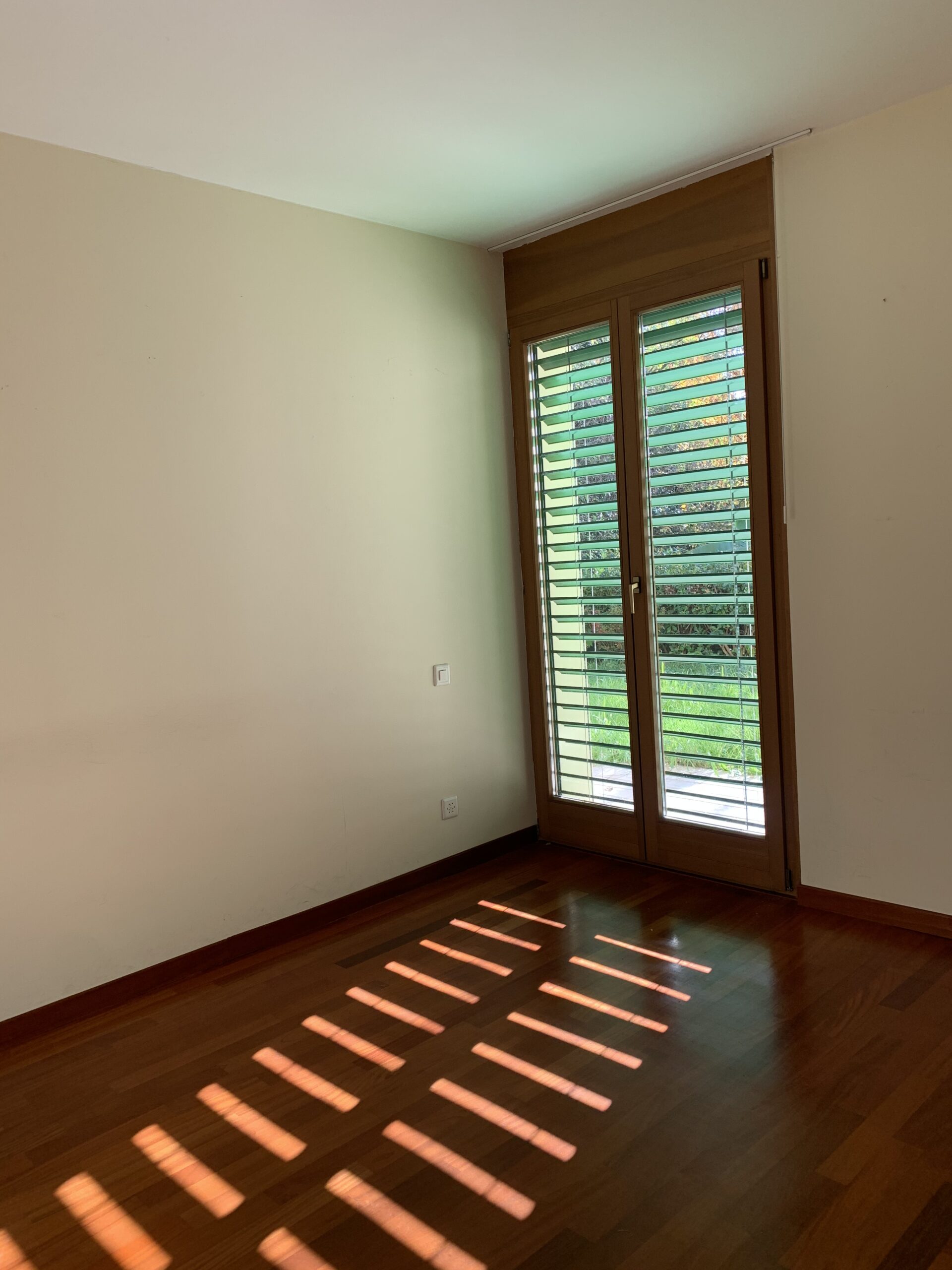 Leerer Raum mit Holzboden und Fenstertür