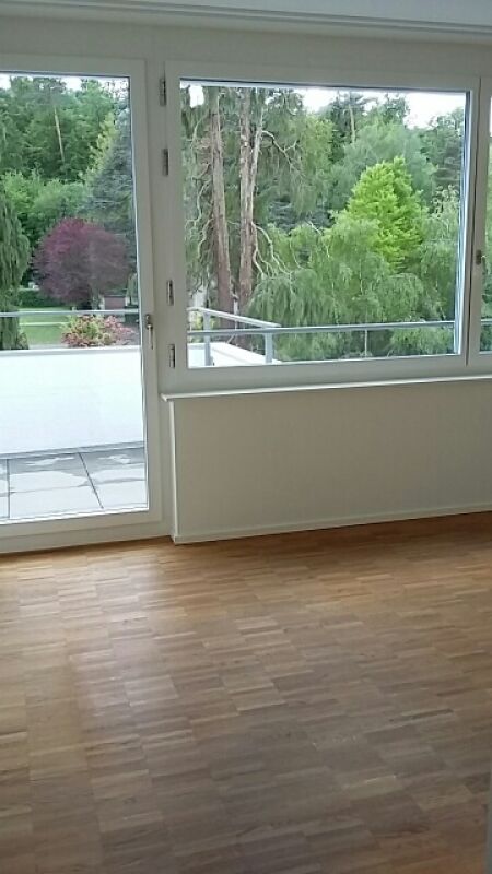 Heller Raum mit großflächiger Fensterfront und Balkonblick