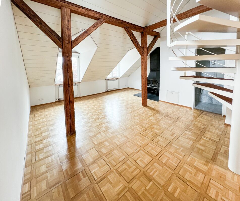 Dachgeschosszimmer mit Holzstützen und Wendeltreppe