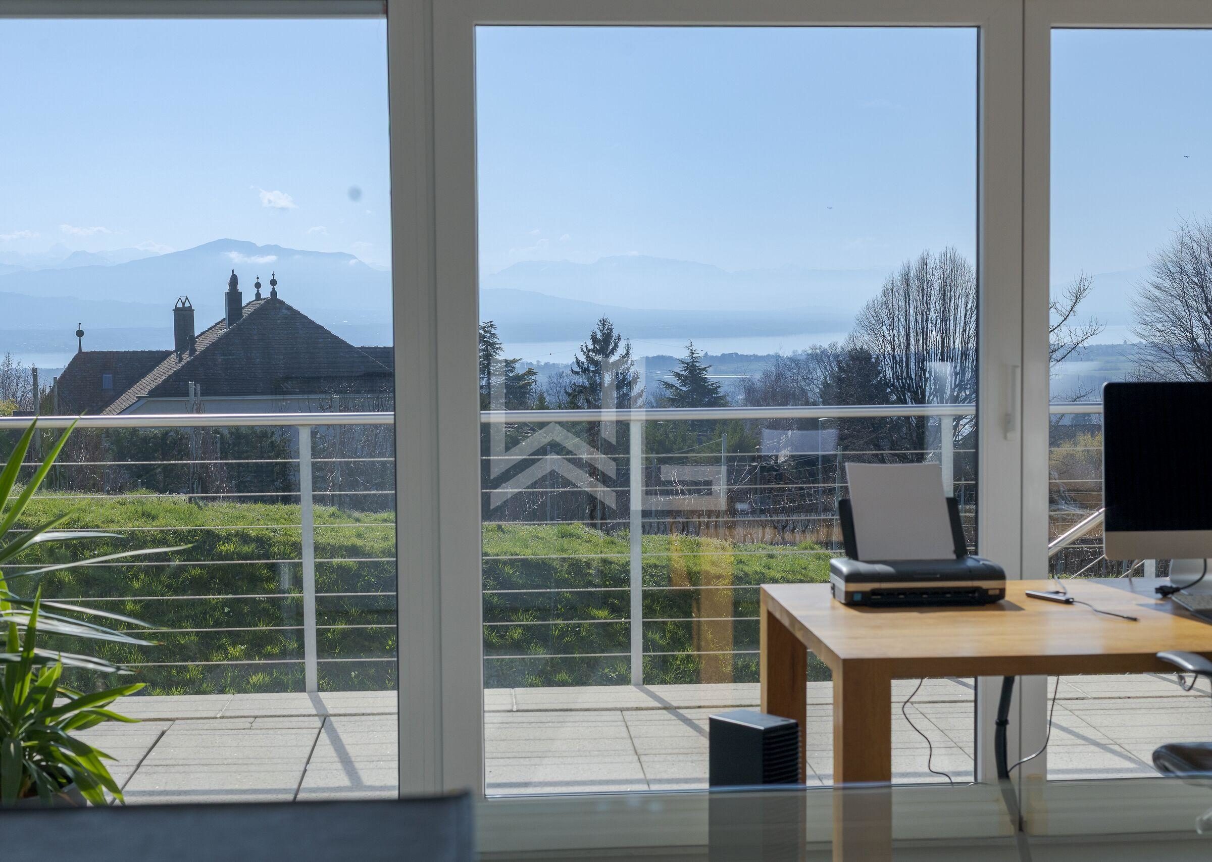 Blick durch große Fenstertüren auf Terrasse und See