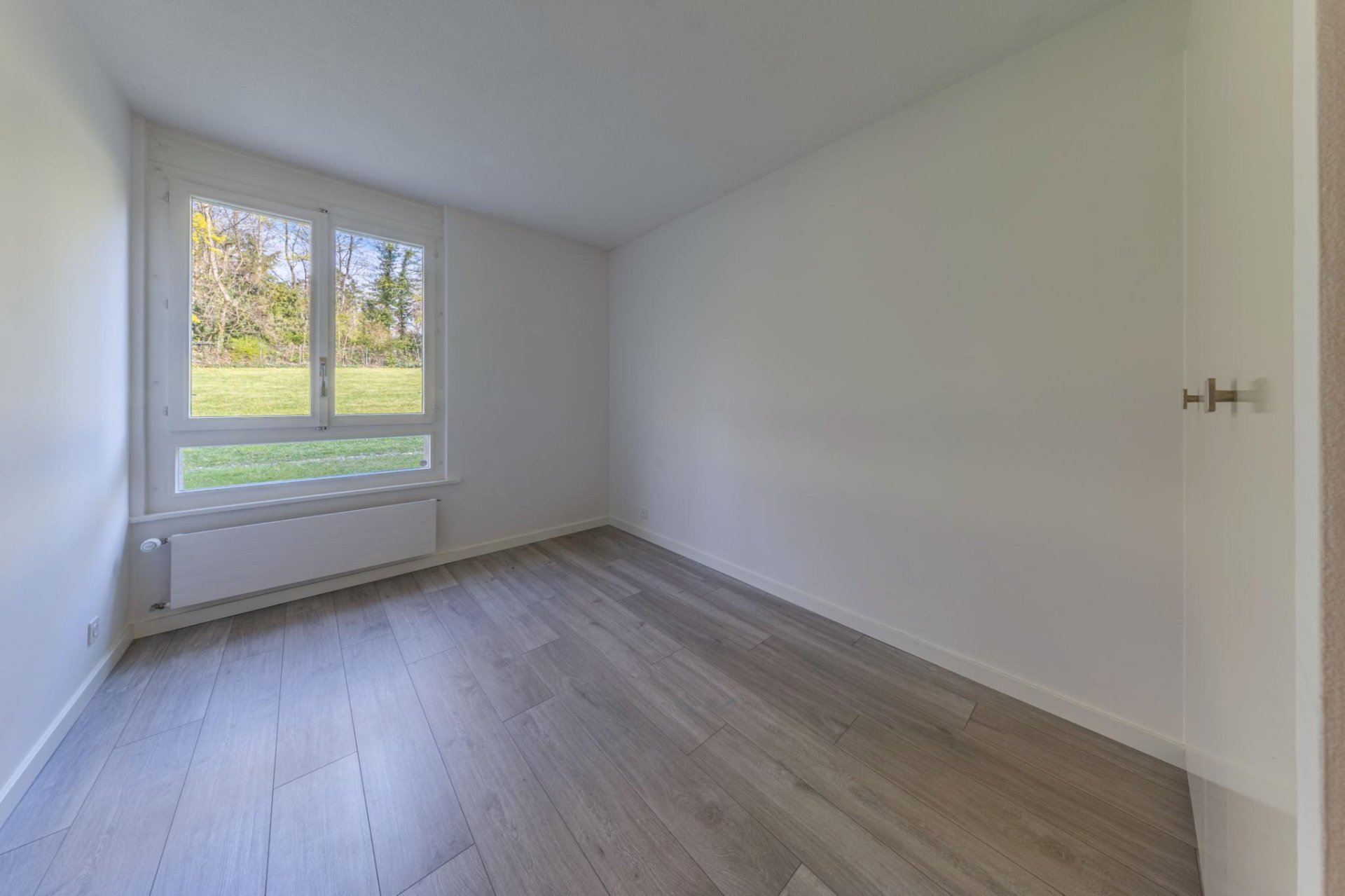 Helles, leeres Zimmer mit Fenster und Heizkörper