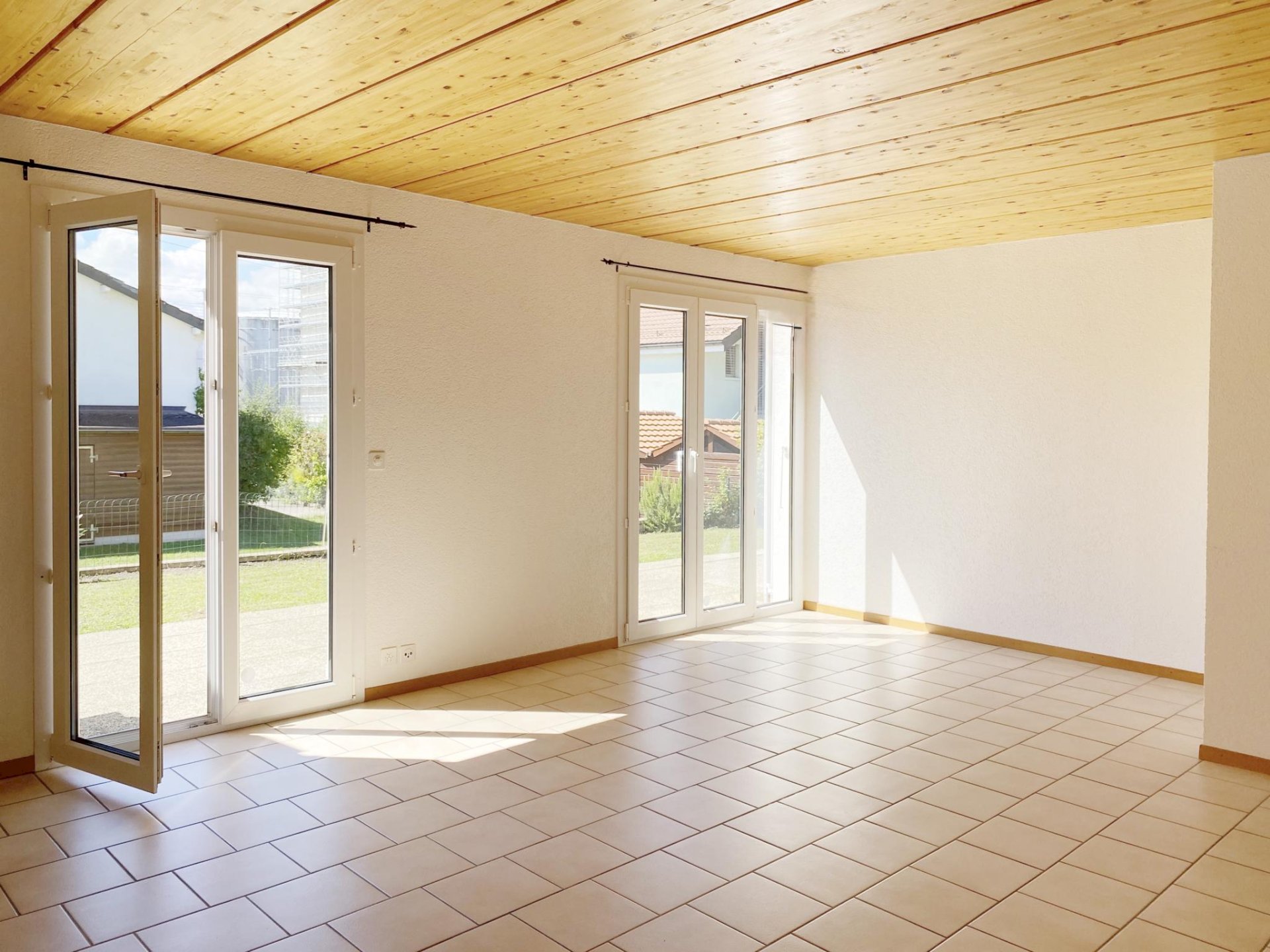 Heller leerer Raum mit Fliesenboden und Holzdecke