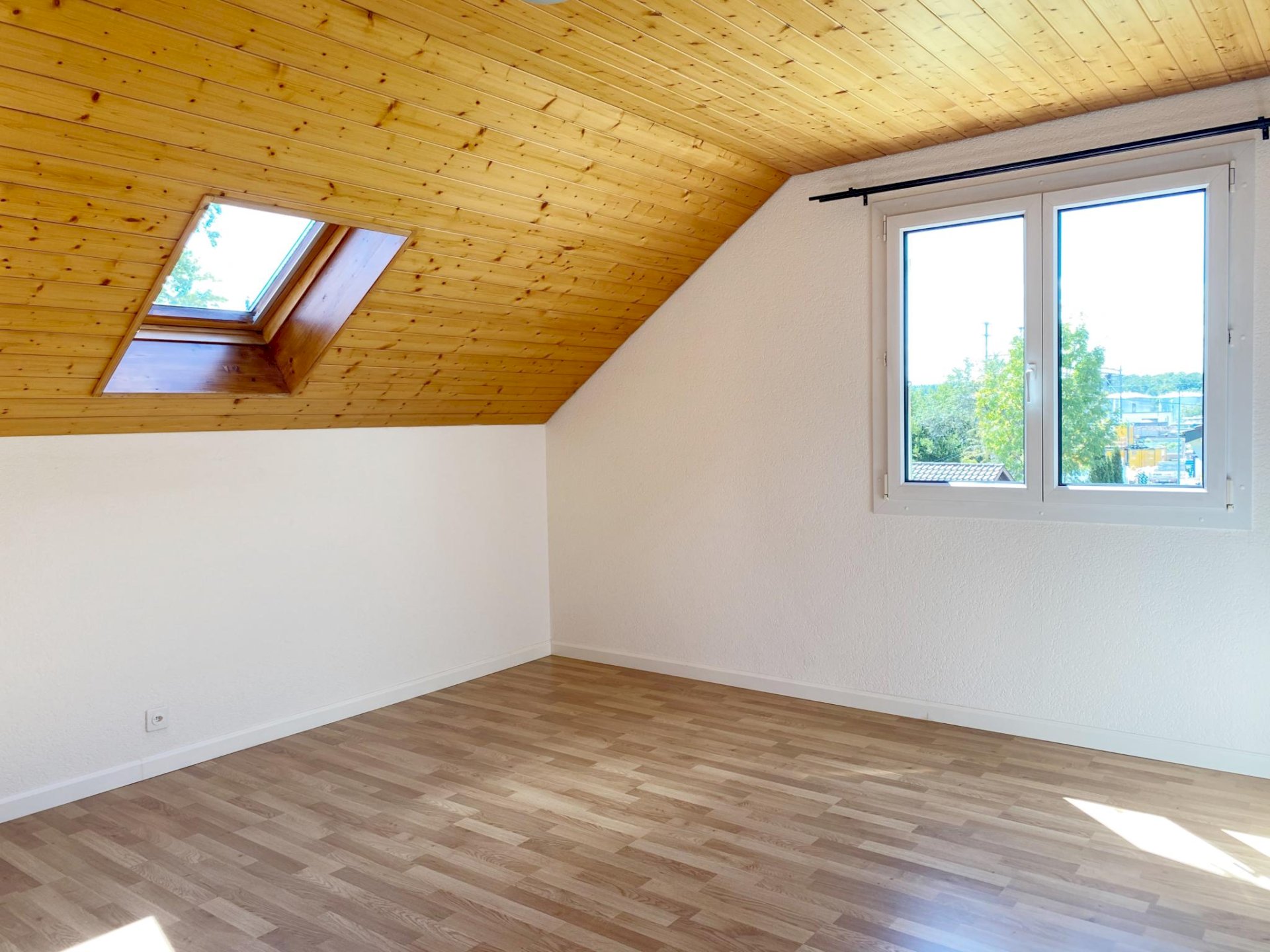 Helles Dachzimmer mit Holzdecke und Dachfenster