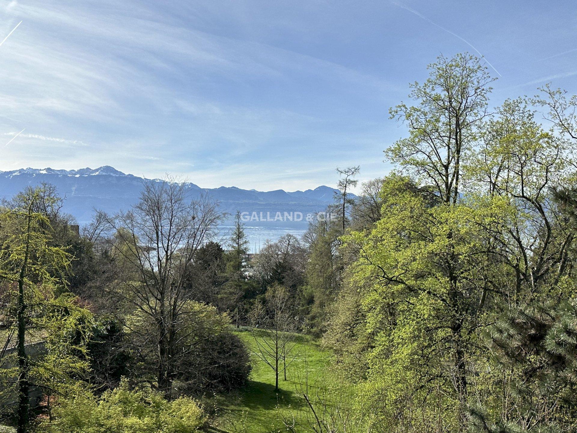 Alpen- und Seeblick über eine grüne Gartenlandschaft