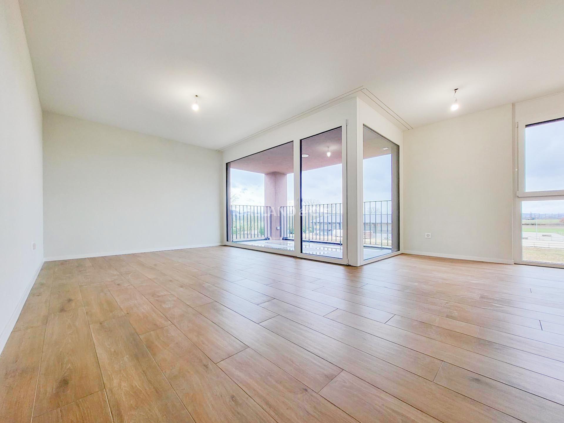 Heller leerer Wohnraum mit großer Glasfront und Balkon