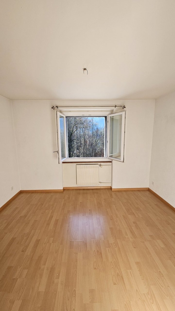 Leerer heller Wohnraum mit Fenster und Laminatboden