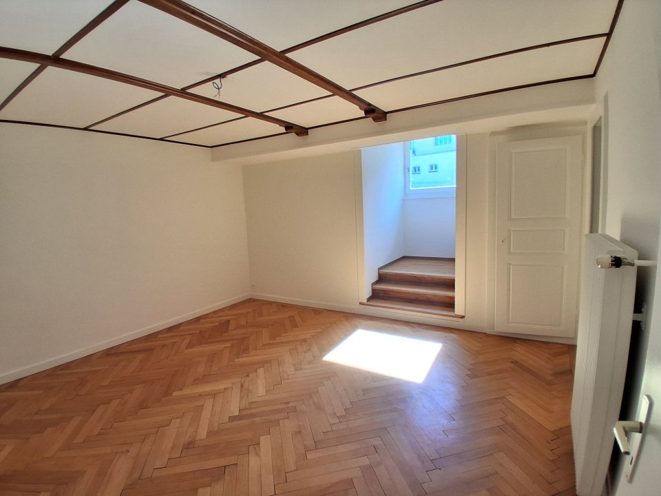 Heller leerer Innenraum mit Fischgrätparkett und Holzdecke