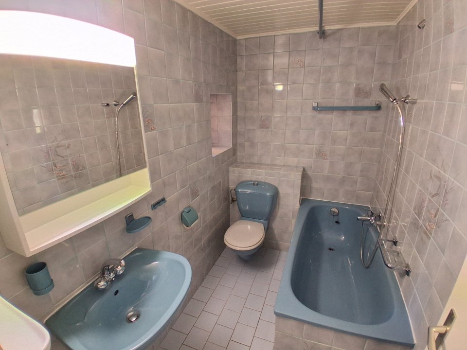Kleines Badezimmer mit Wanne und blauem Keramikwaschbecken