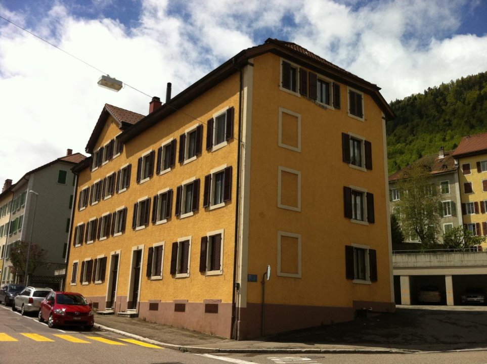 Wohnhaus mit gelber Fassade an einer Straße