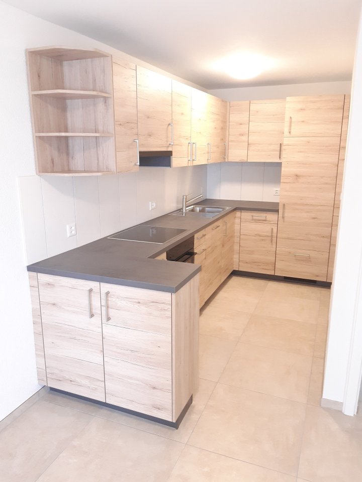 Offene Einbauküche mit Holzoptik und dunkler Arbeitsplatte