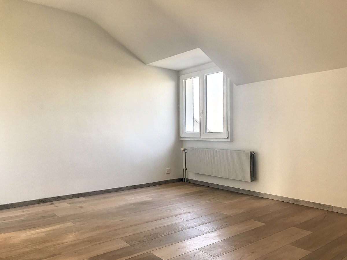 Leerer Dachgeschossraum mit Fenster und Heizkörper