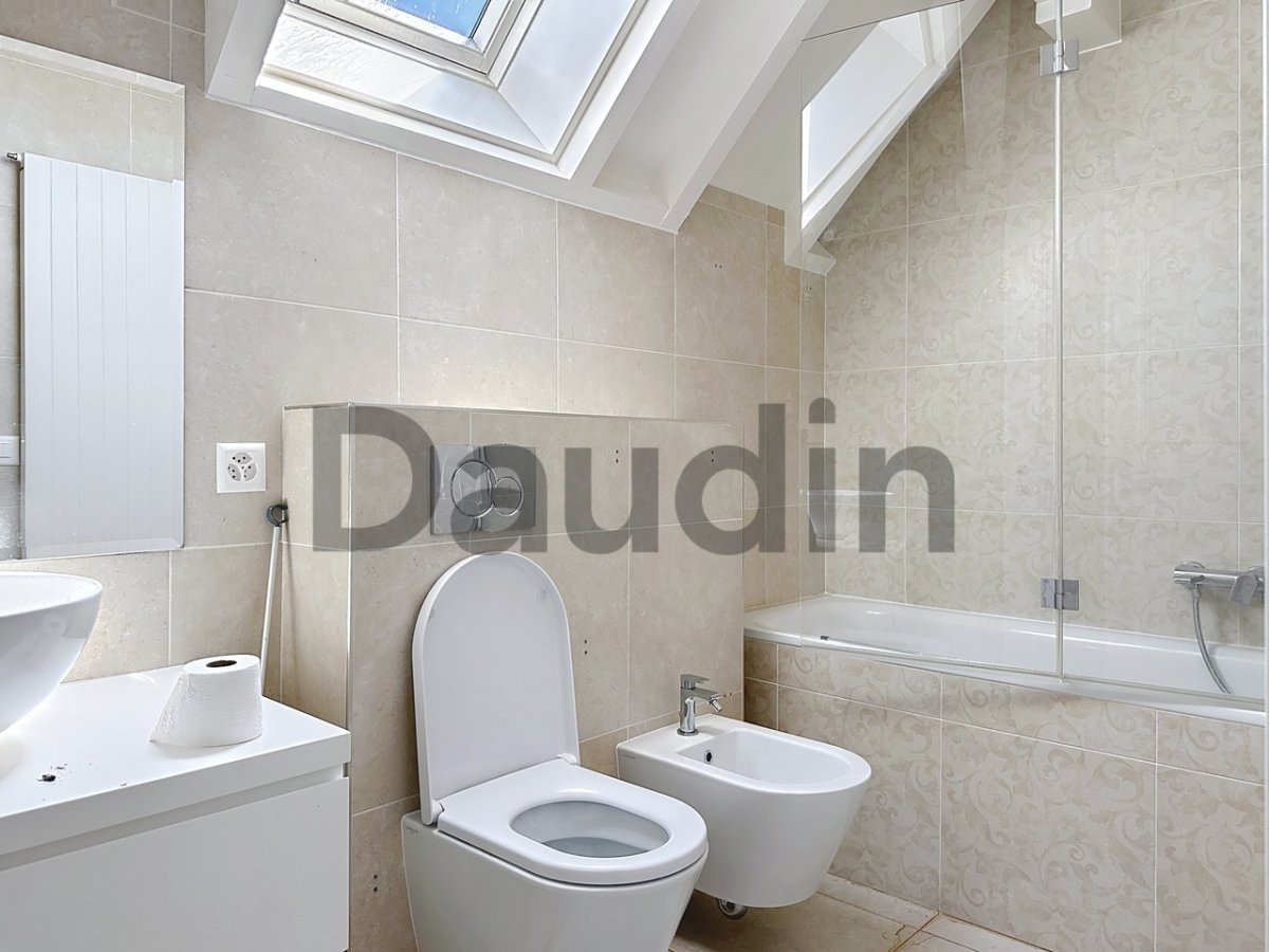 Helles Badezimmer mit Badewanne, Toilette und Dachfenster