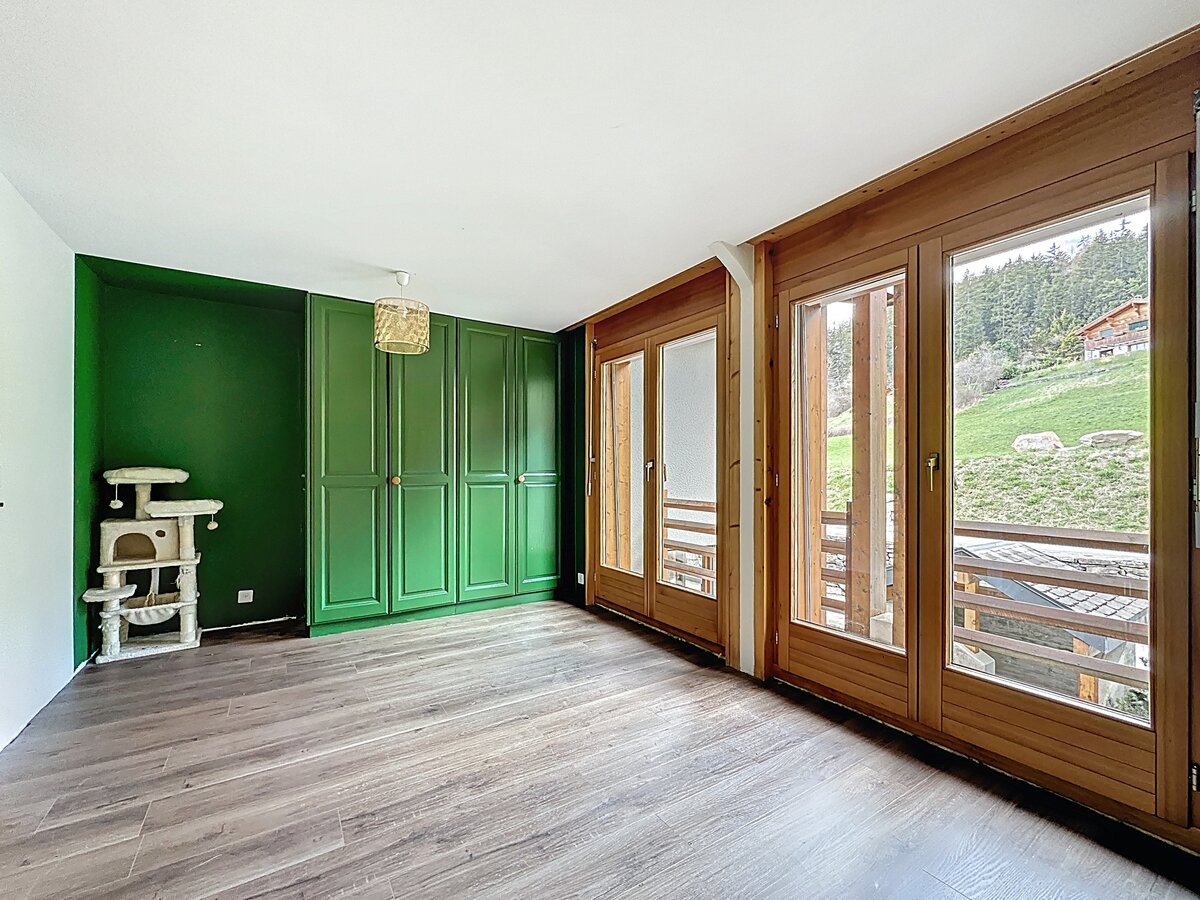Zimmer mit grünem Einbauschrank und großen Holzfenstern