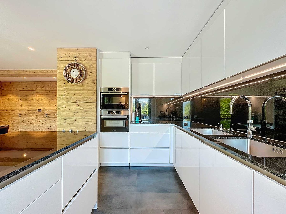 Moderne weiße Designküche mit dunkler Arbeitsfläche