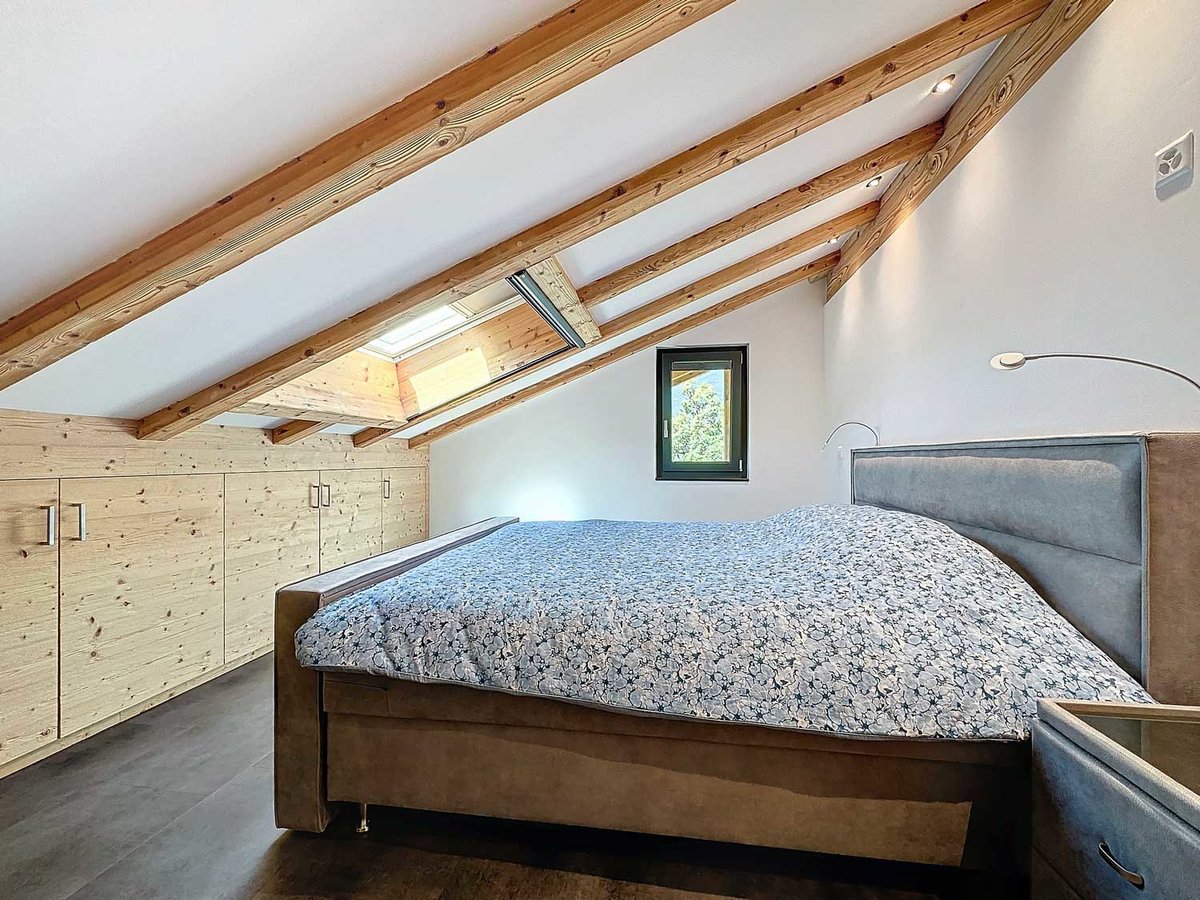 Dachgeschoss-Schlafzimmer mit sichtbaren Holzbalken