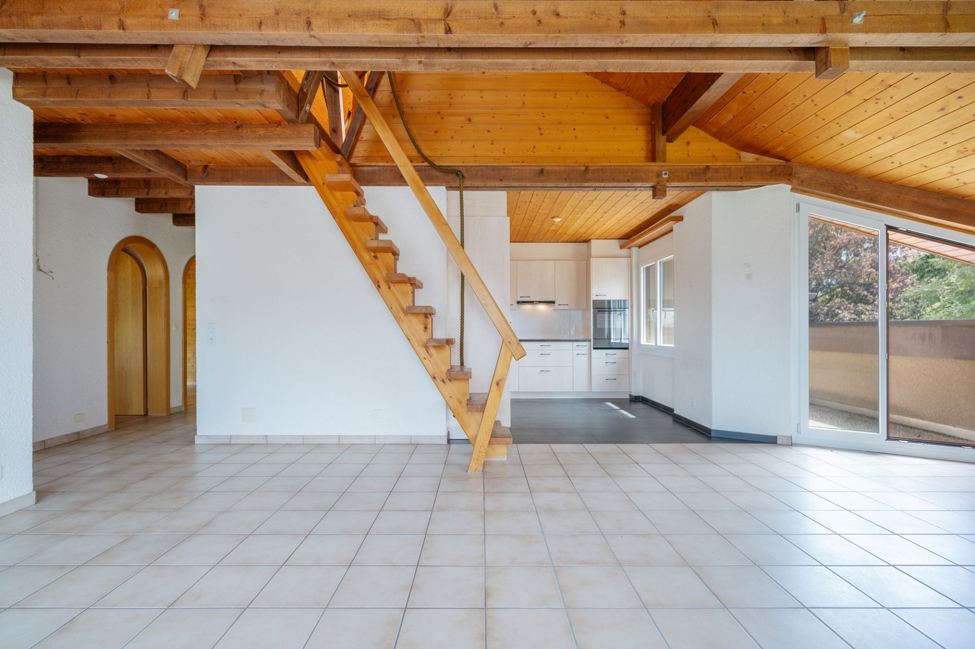 Offener Wohnbereich mit Holztreppe und sichtbarer Küche