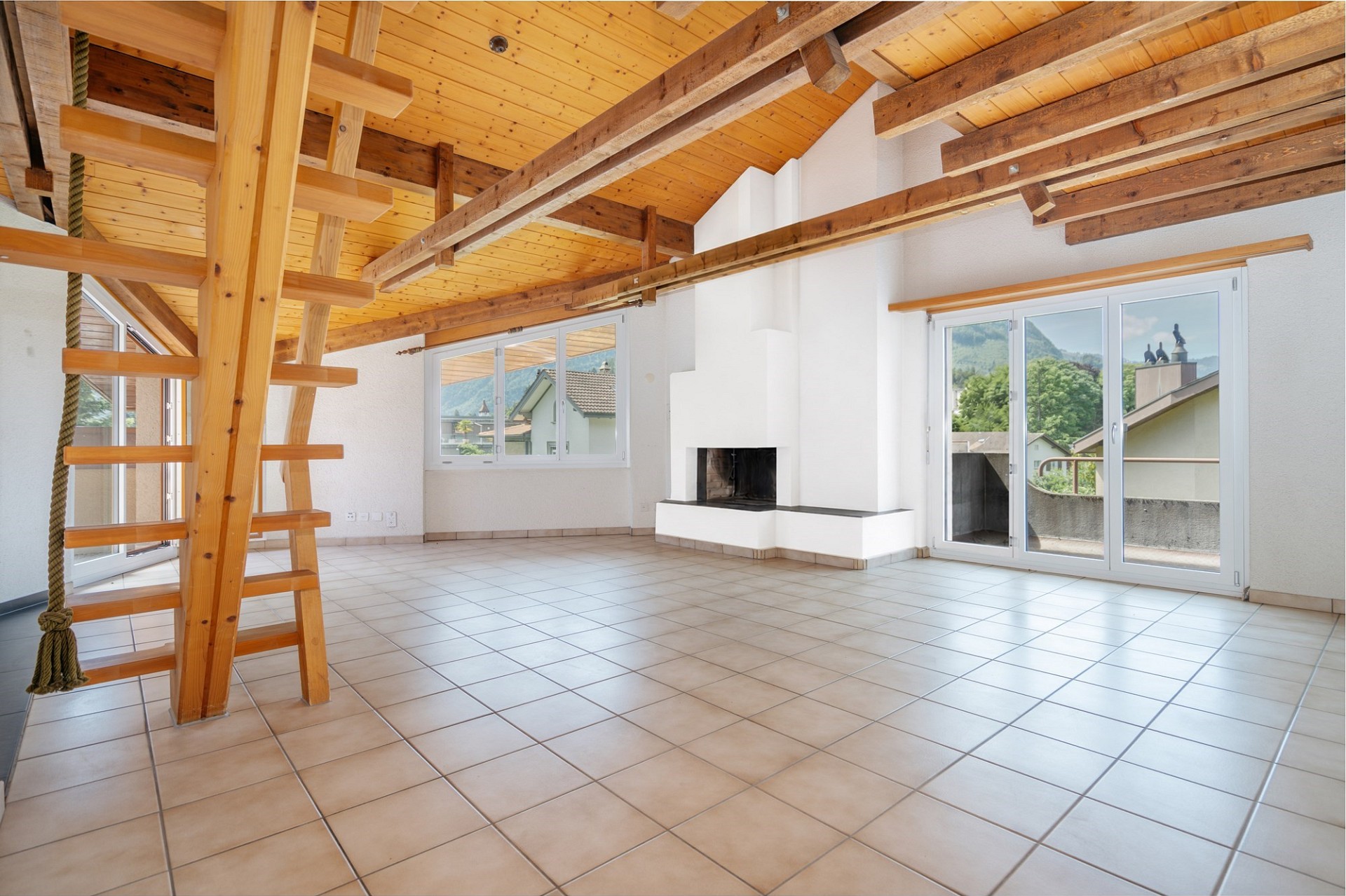 Heller Wohnraum mit Holzdecke, sichtbaren Balken und Kamin