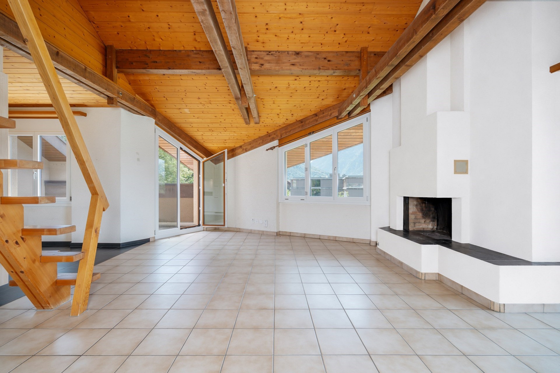 Großer Wohnraum mit Holzdecke und Kamin