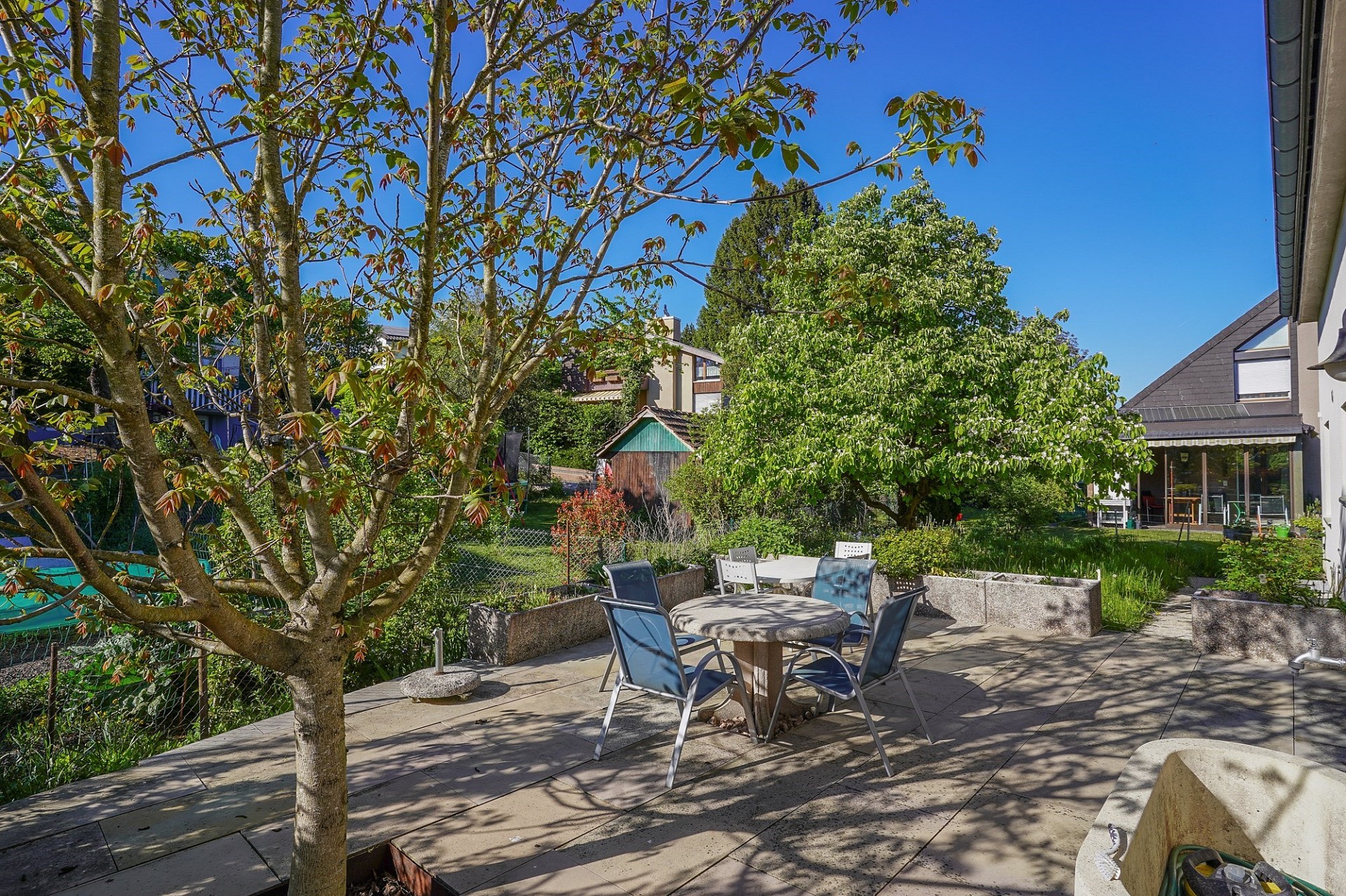 Große Terrasse mit Gartenmöbeln und üppigem Grün