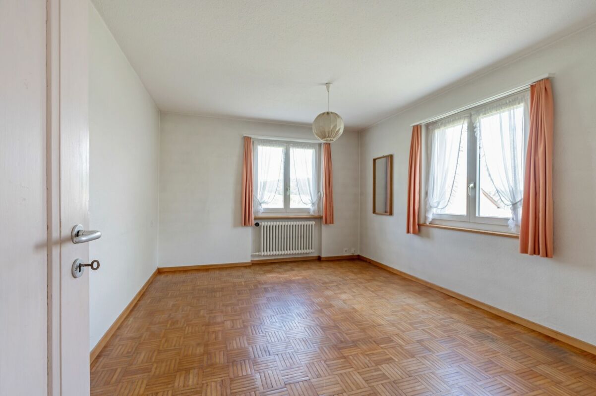 Leeres Schlafzimmer mit Parkett und Fenstern