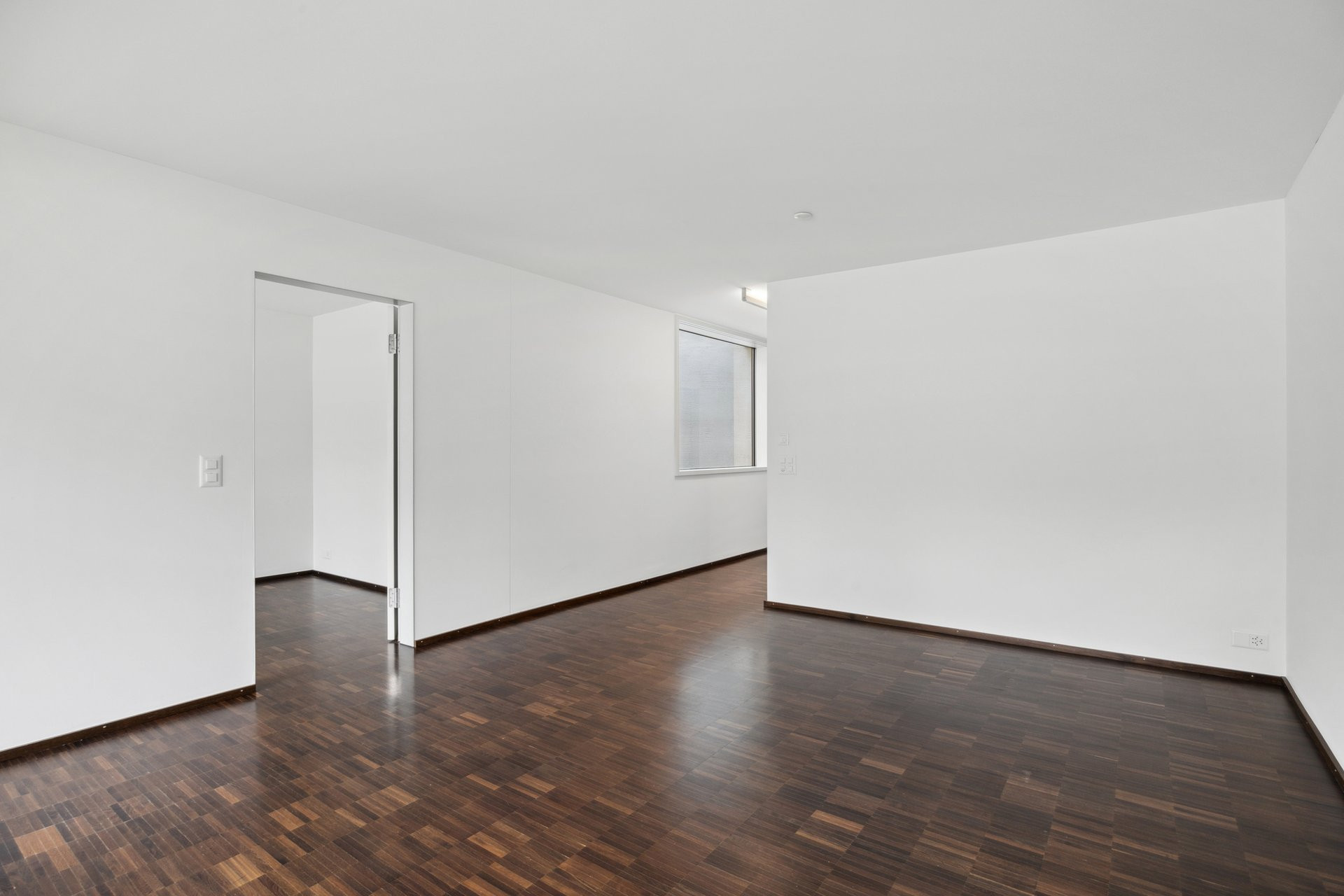 Leerer, modern renovierter Innenraum mit dunklem Holzboden