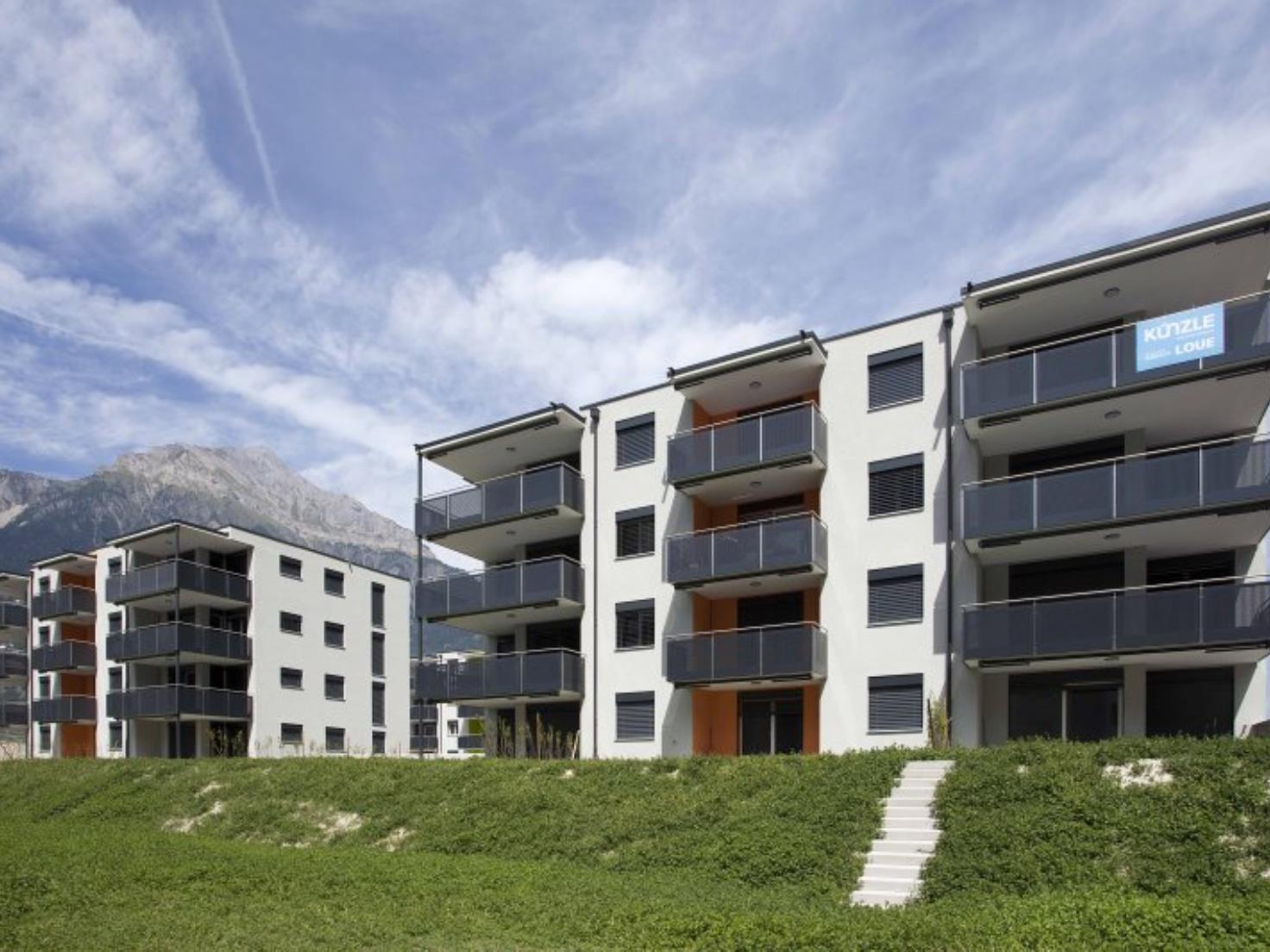 Moderne Wohnanlage mit Balkonen vor Bergkulisse