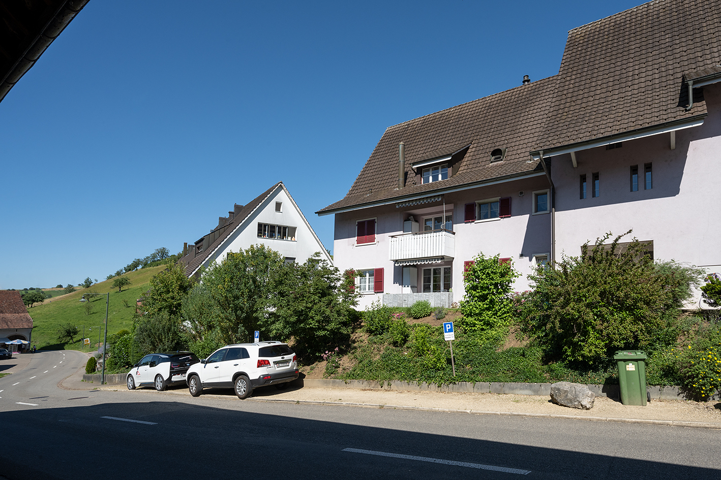 Wohnhäuser an einer Hanglage mit Straße und Parkplatz