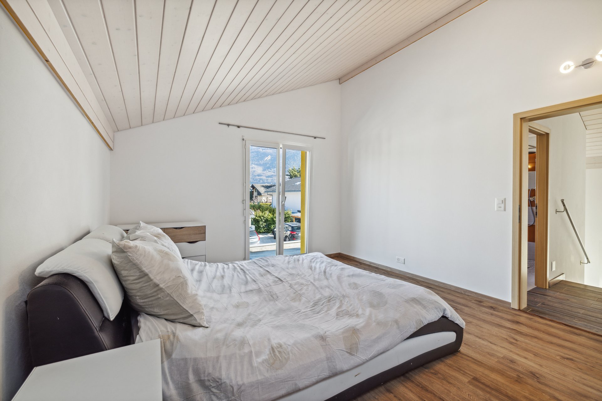 Schlafzimmer mit Dachschräge und Balkonblick
