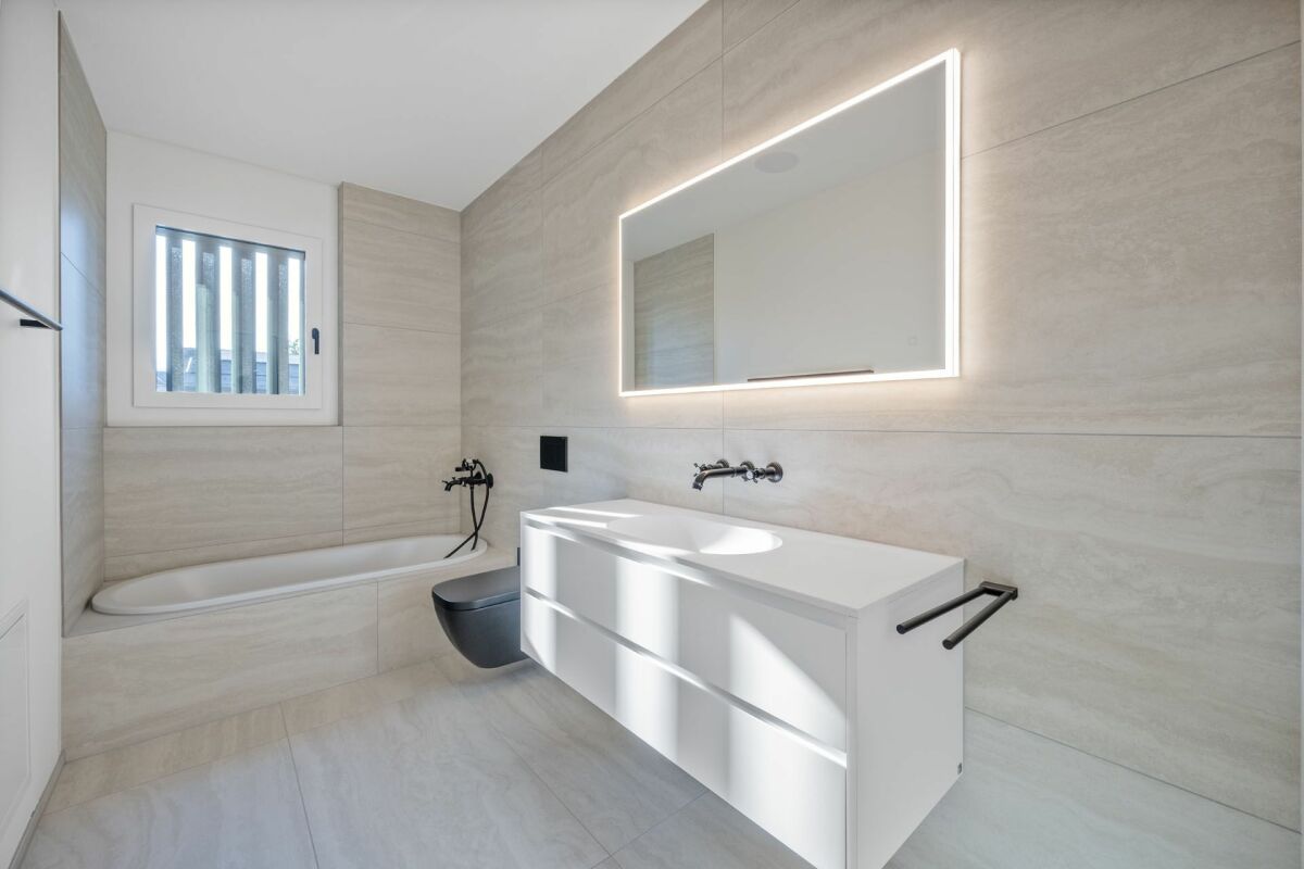 Modernes Badezimmer mit Badewanne und beleuchtetem Spiegel