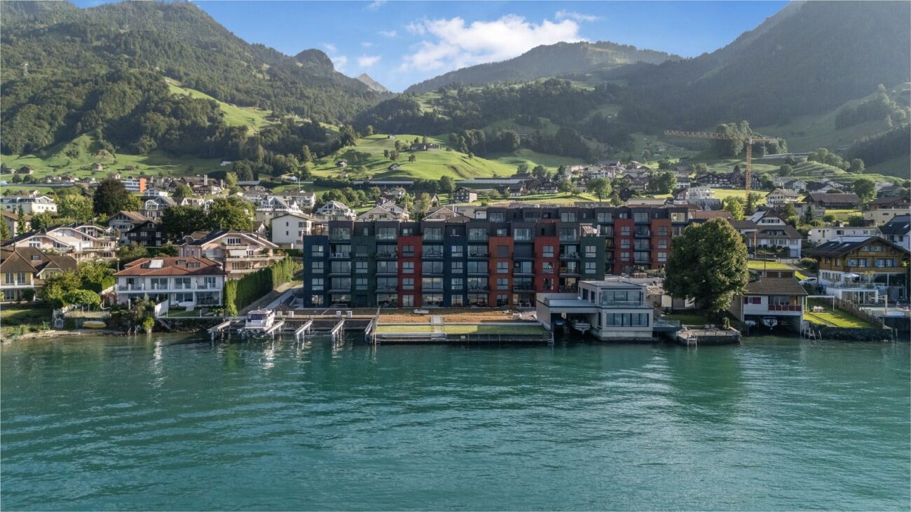 Seeblick auf Wohnbebauung vor Bergkulisse