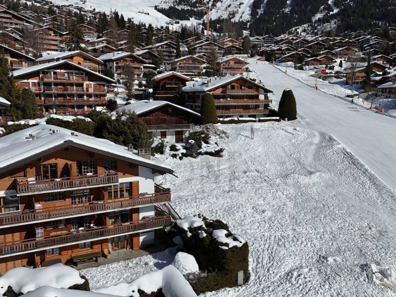 Verschneite Bergsiedlung mit Chalets und Skipiste