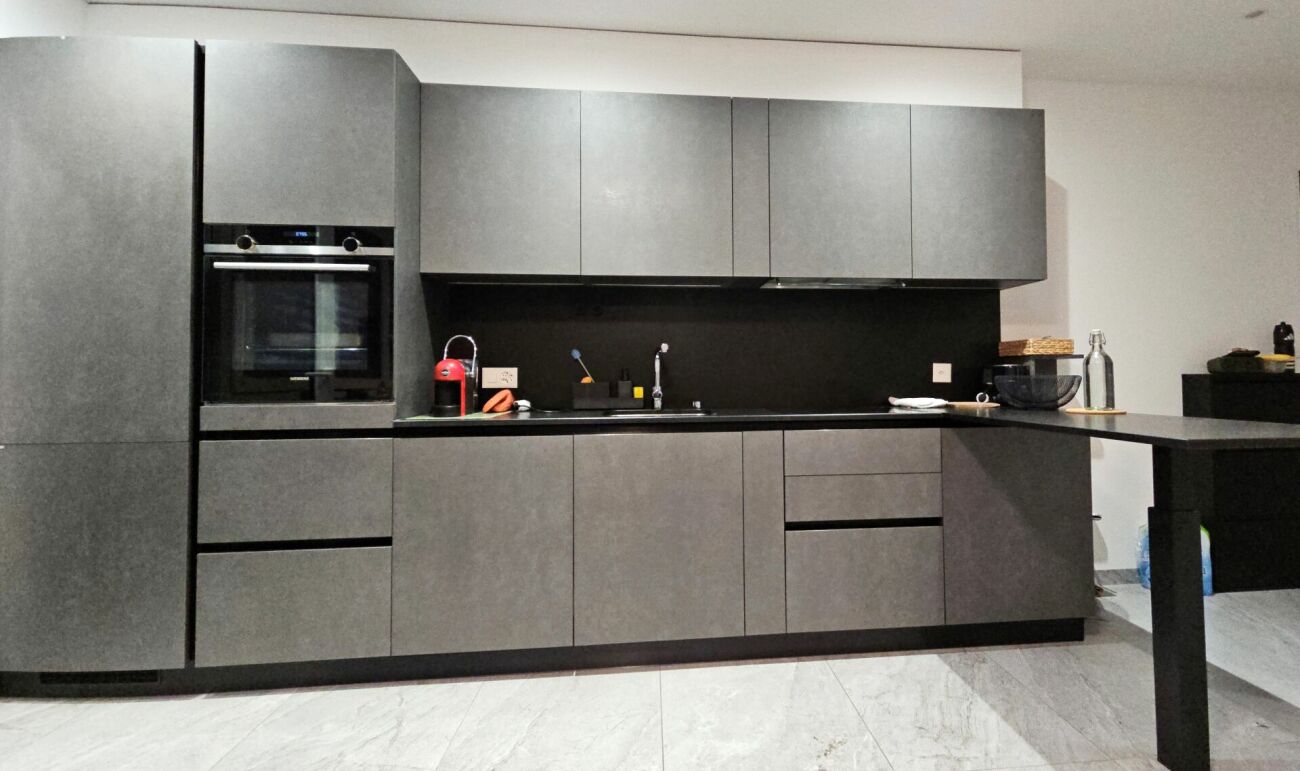 Moderne graue Küche mit schwarzer Rückwand