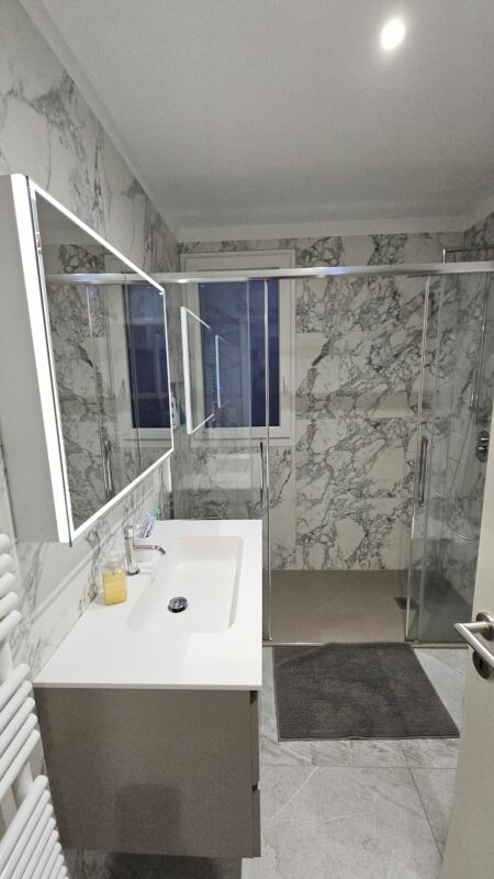 Modernes Badezimmer mit Marmoroptik und Glasdusche