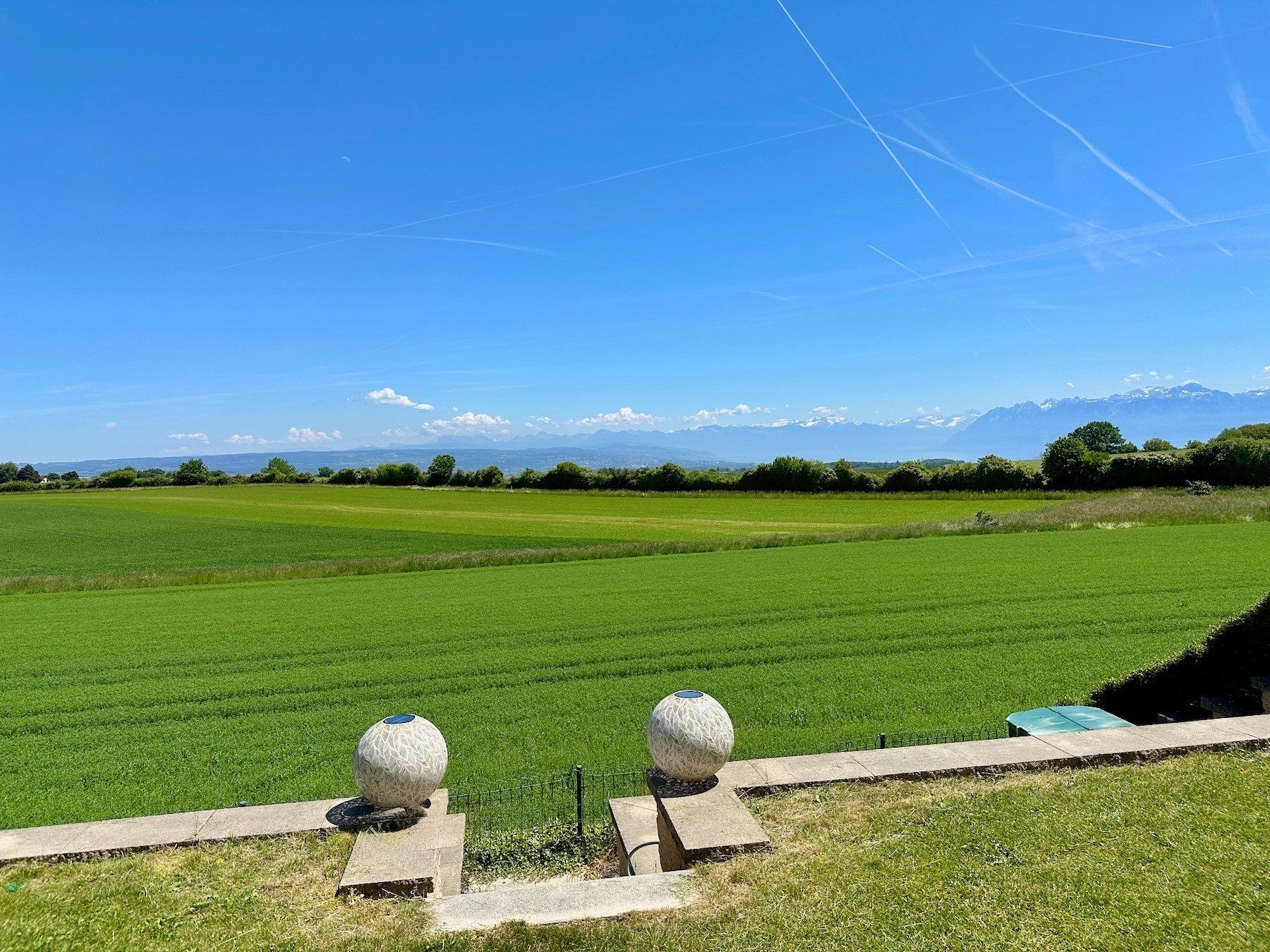 Panoramischer Blick über grüne Felder mit Bergkulisse