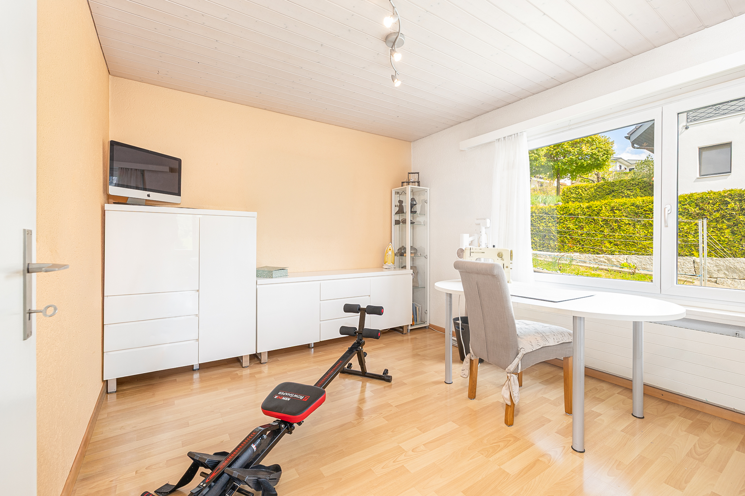 Heller Arbeitsraum mit Schreibtisch und Trainingsbank