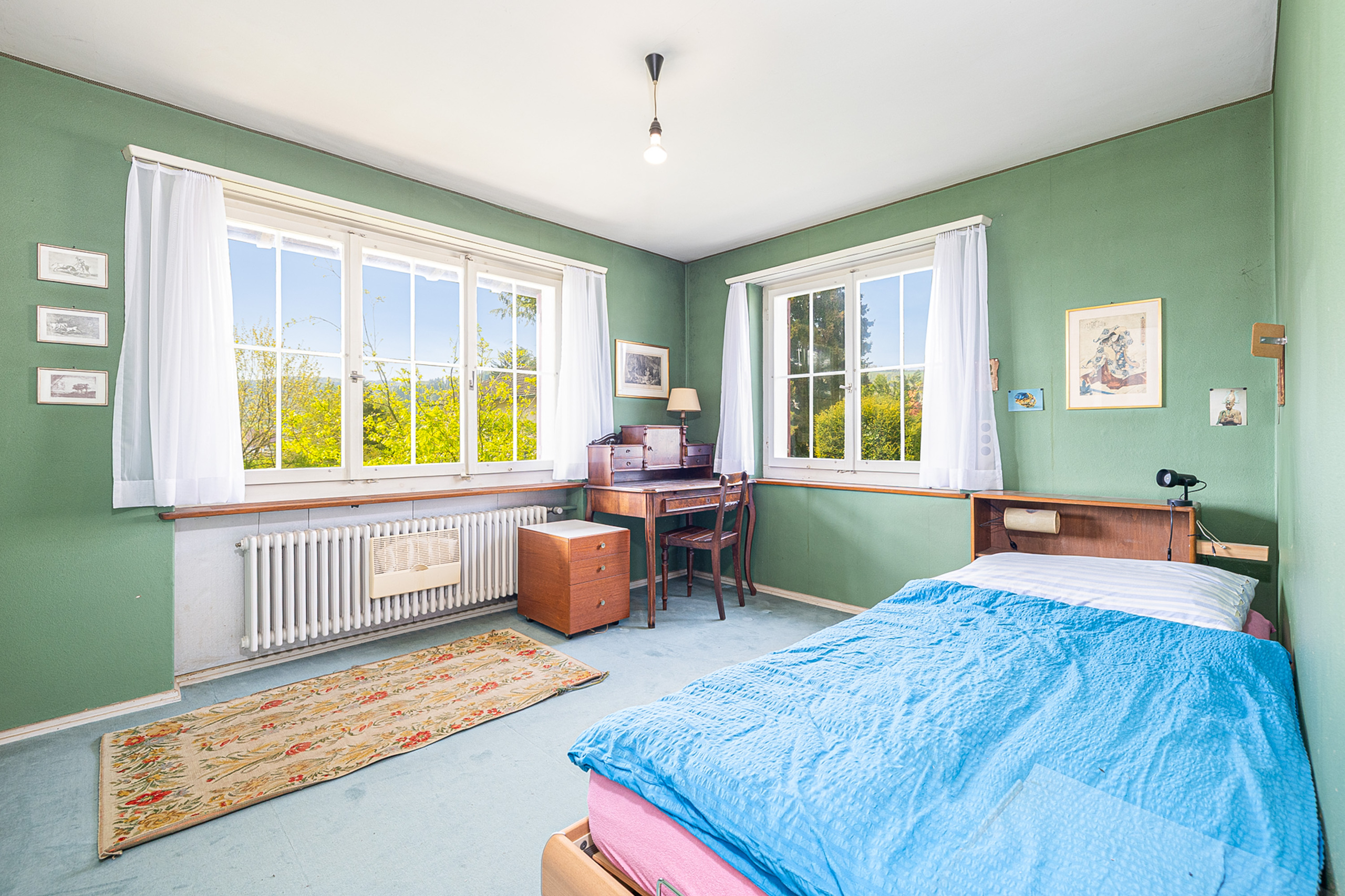 Schlafzimmer mit großen Fenstern und Vintage-Möblierung