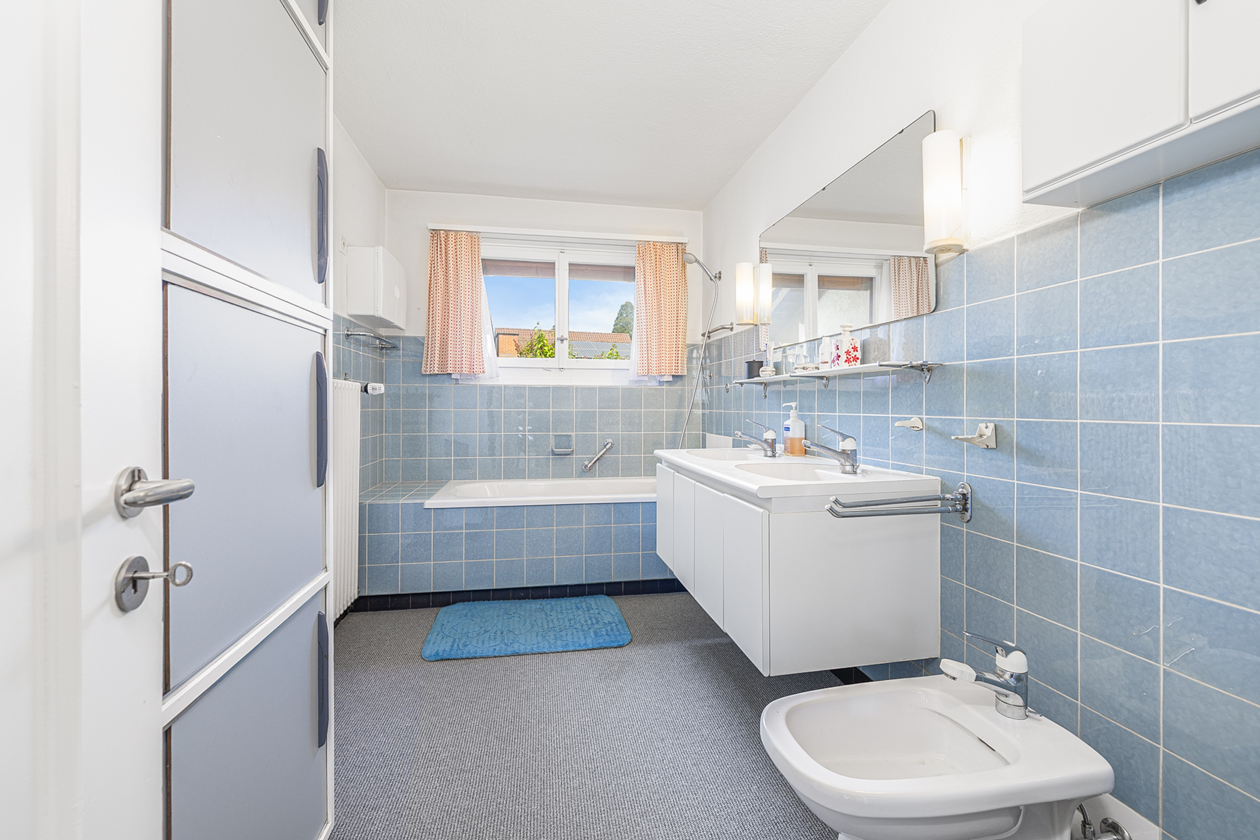 Badezimmer mit blau gefliesten Wänden und Badewanne