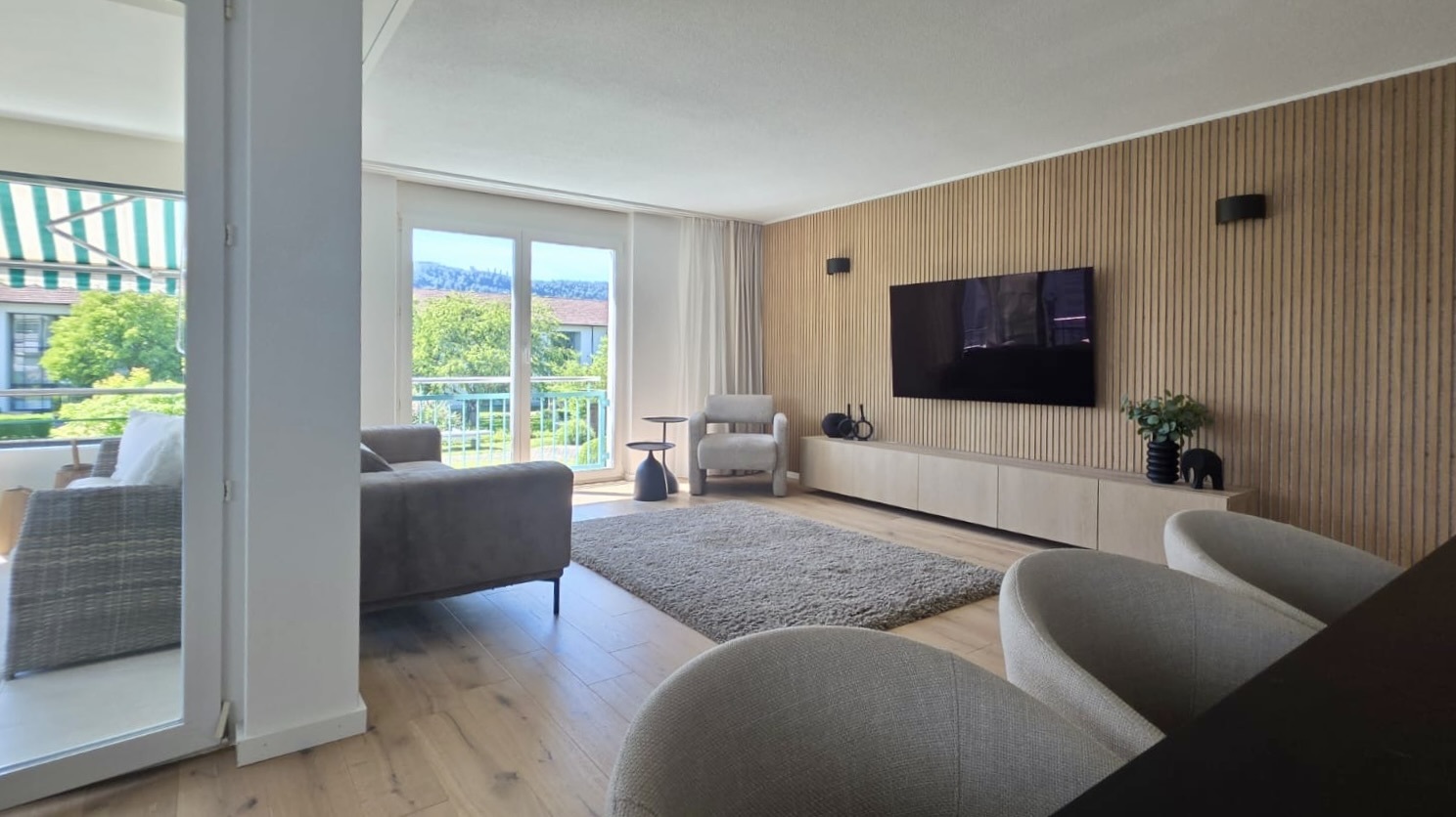 Heller Wohnraum mit Holzlamellenwand und Balkonblick