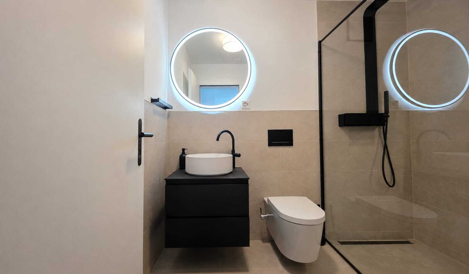Modernes Badezimmer mit beleuchteten Rundspiegeln