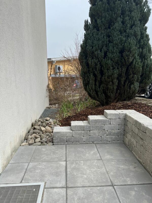 Außenbereich mit gepflasterter Terrasse und Gartenbepflanzung