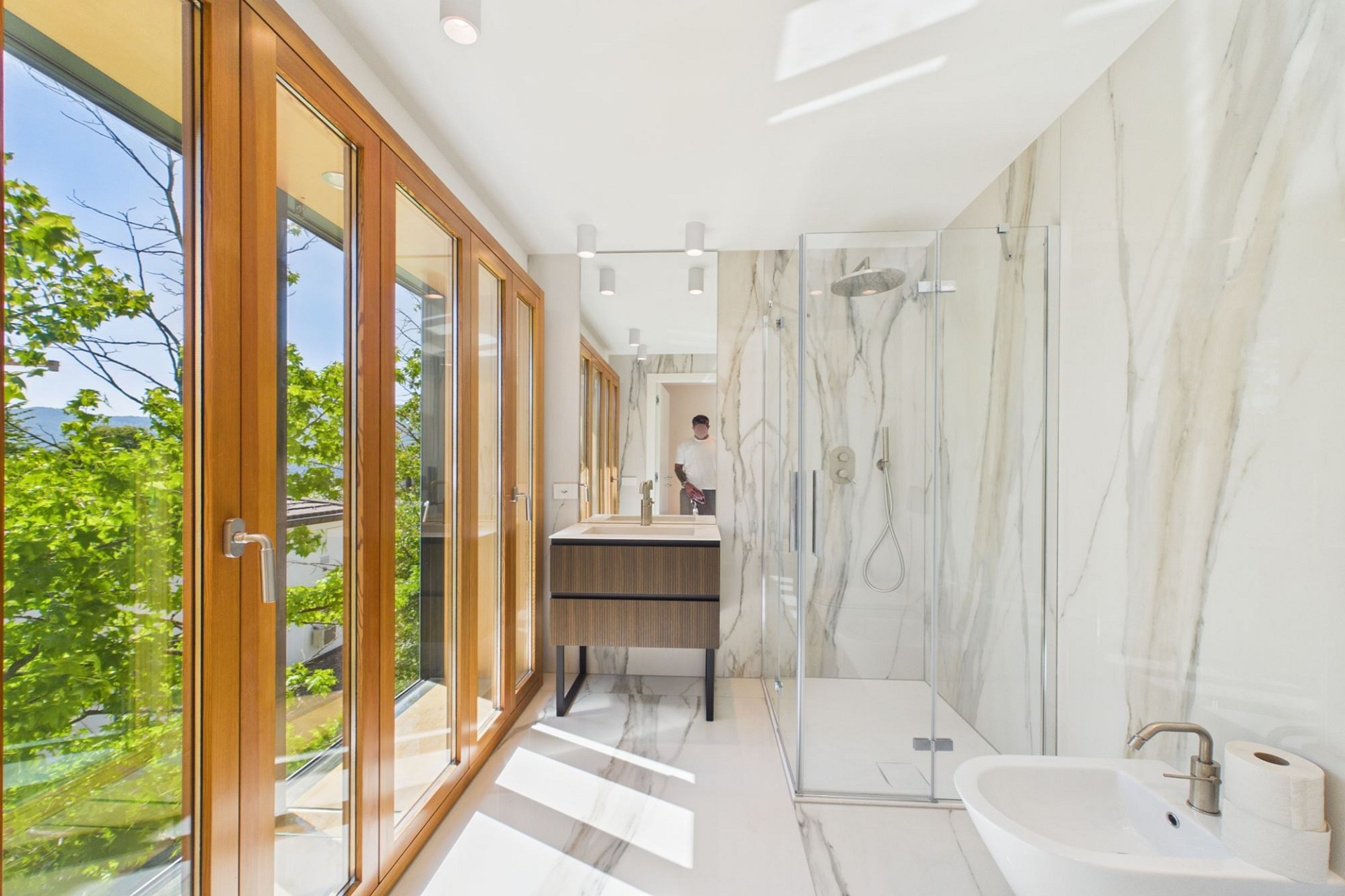 Helles, modernes Badezimmer mit bodentiefen Fenstern und großer Dusche