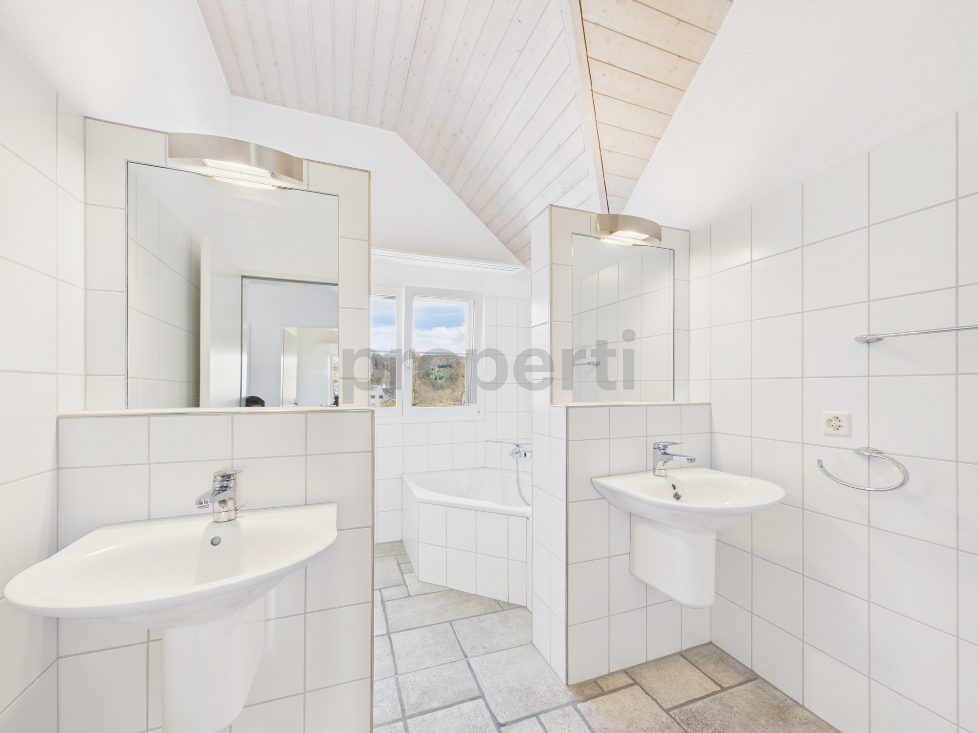 Helles Badezimmer mit zwei Waschbecken und Dachschräge