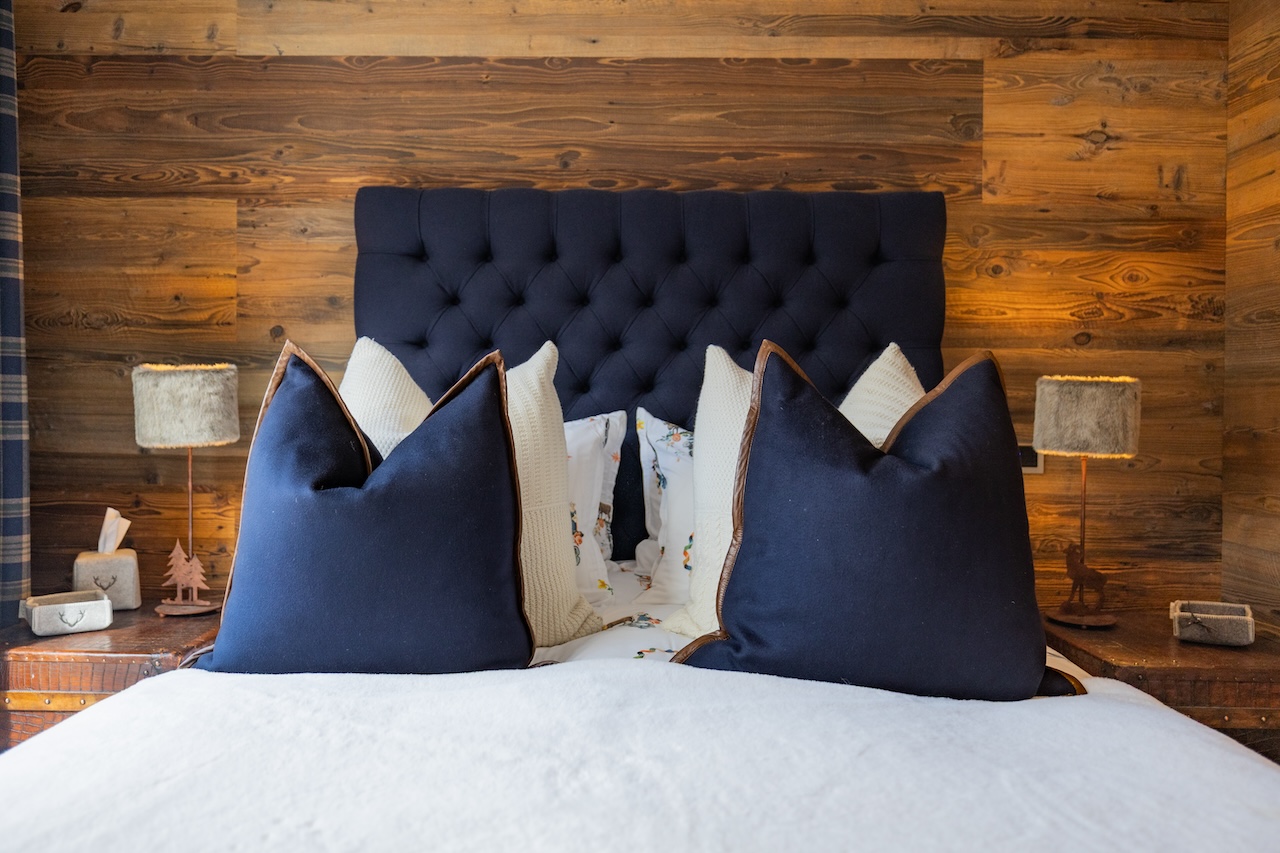 Gemütliches Schlafzimmer mit dunklem gepolstertem Kopfteil und Holzpaneelwand