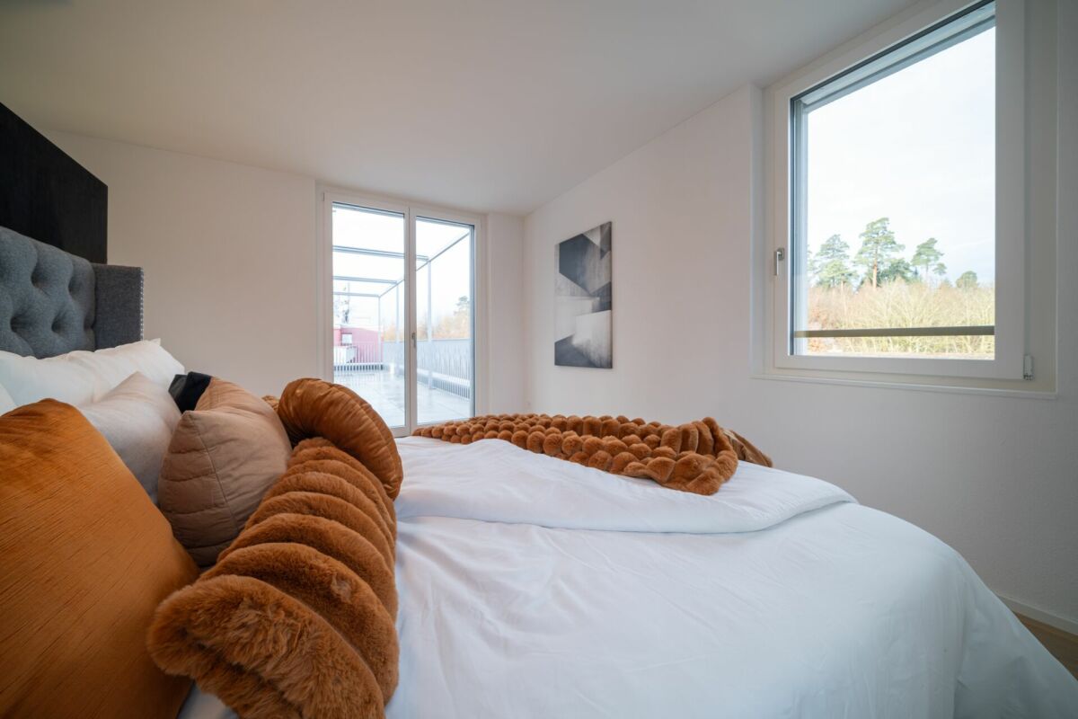 Helles Schlafzimmer mit großen Fenstern und Bett
