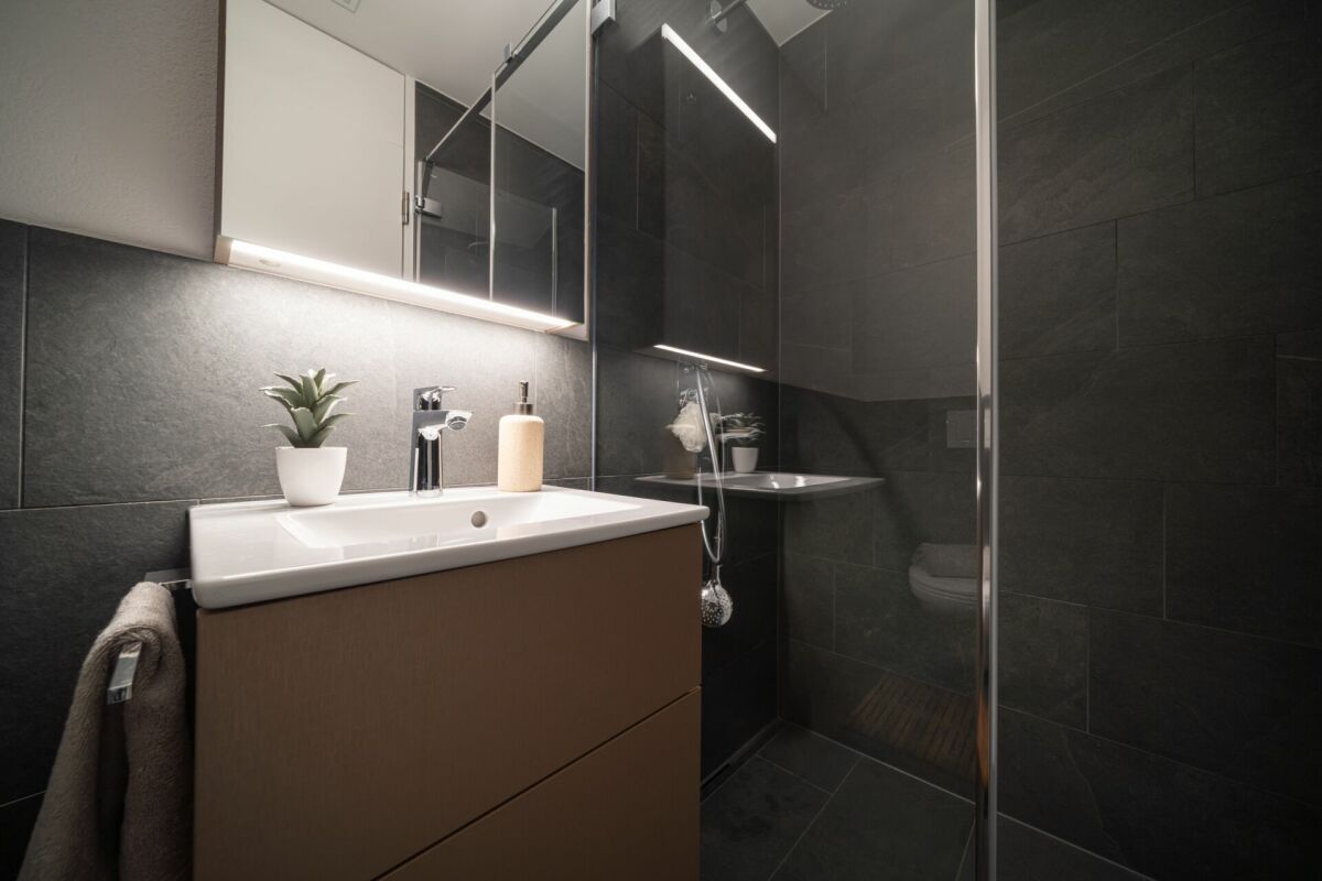 Modernes dunkles Badezimmer mit Waschbecken und Dusche