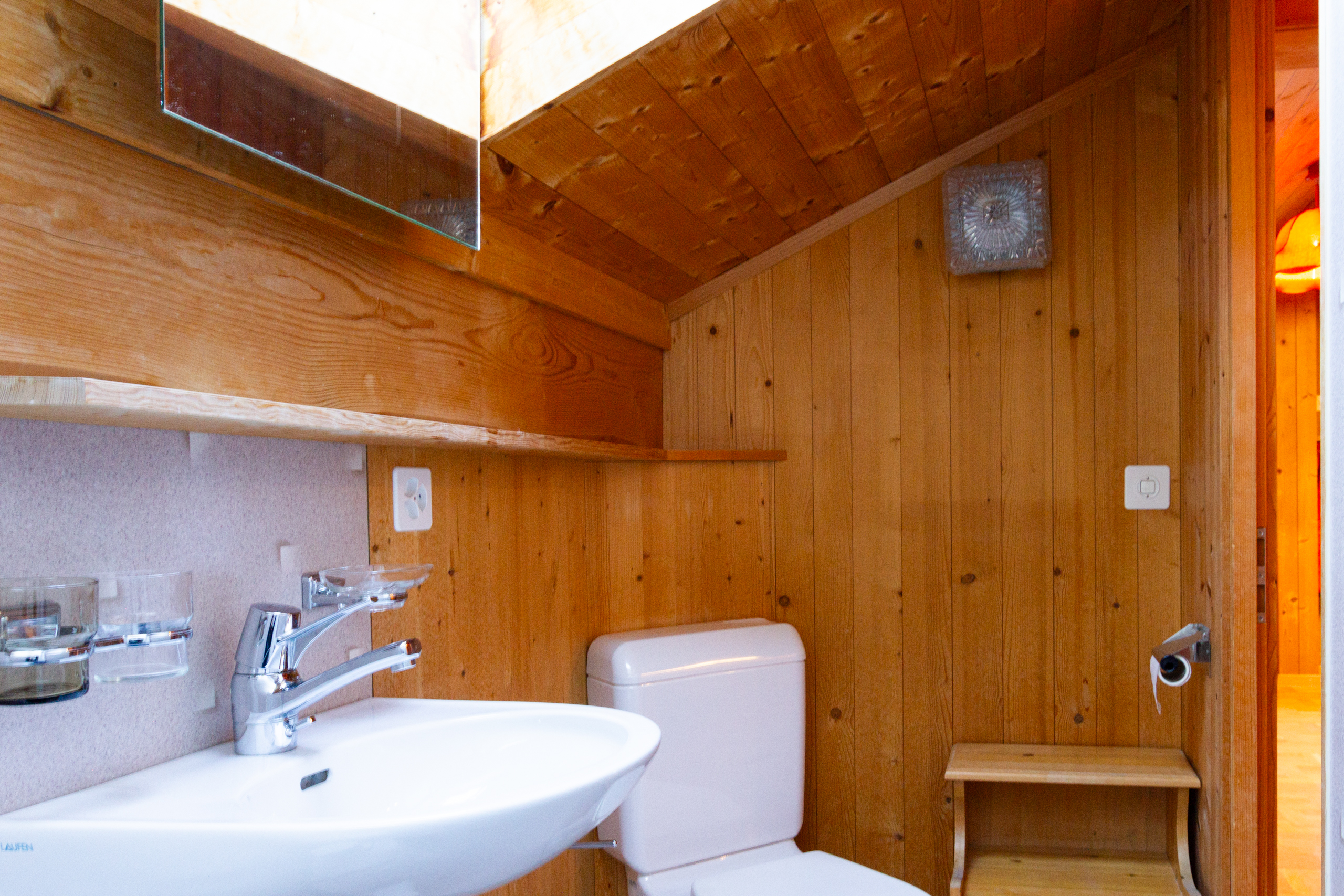 Kleines Holzbadezimmer mit WC und Waschbecken