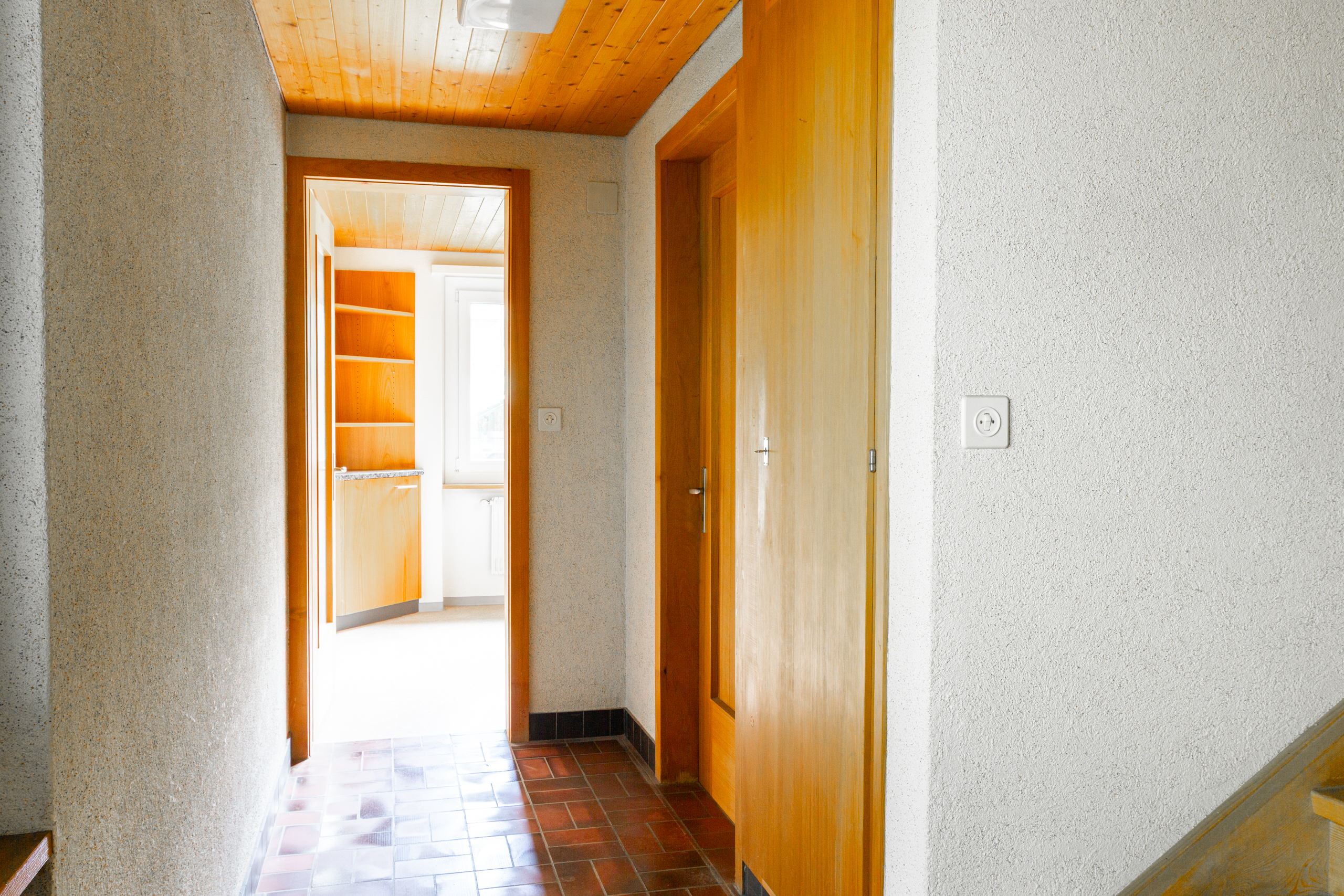 Flur mit Holzdecken und Blick in einen hellen Raum