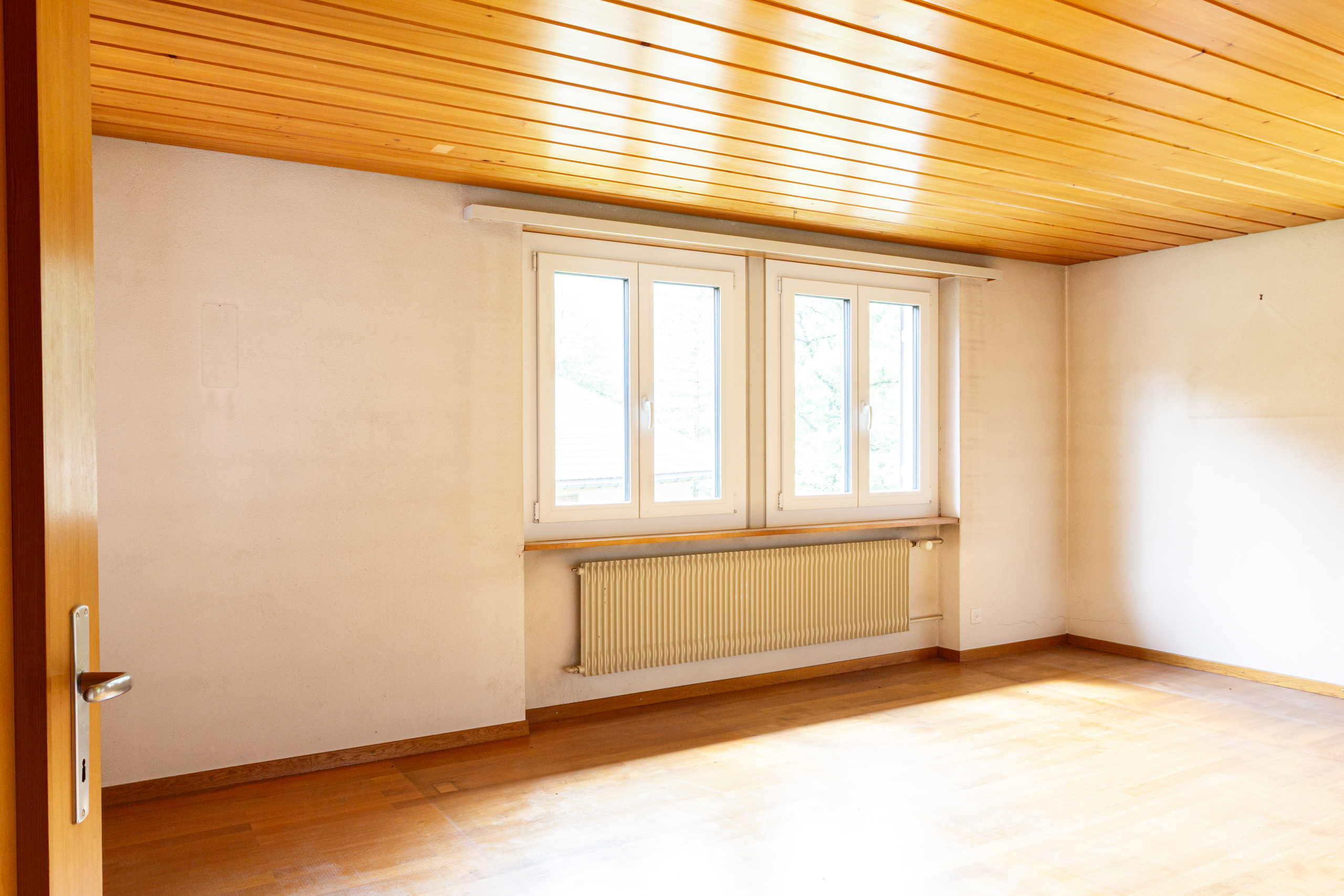 Leerer Raum mit Holzdecke und Heizkörper